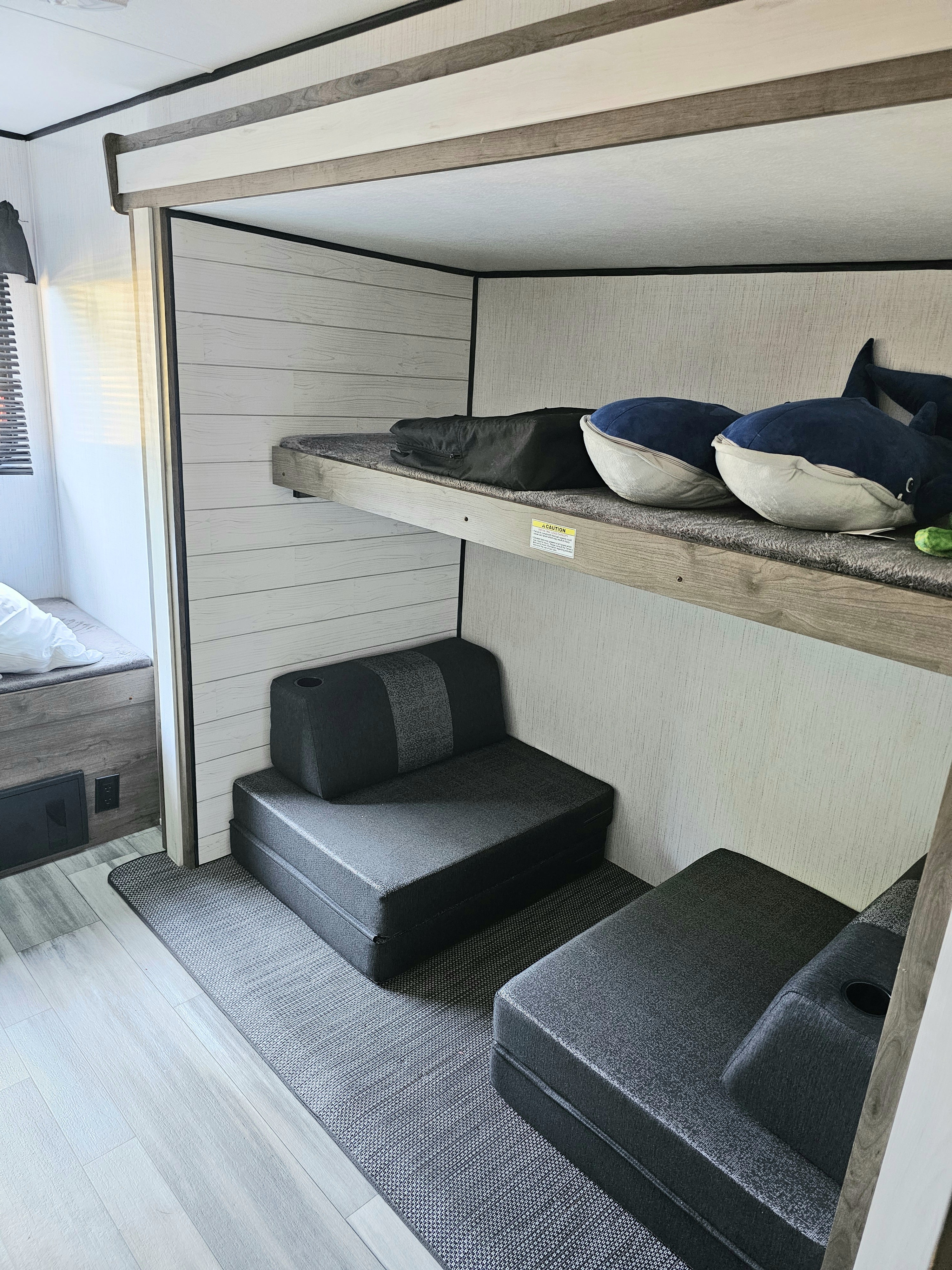 Modern RV rental interior: bunk beds, two convertible seats below, and light wood-look accents.. Heartland RVs Pioneer 2022