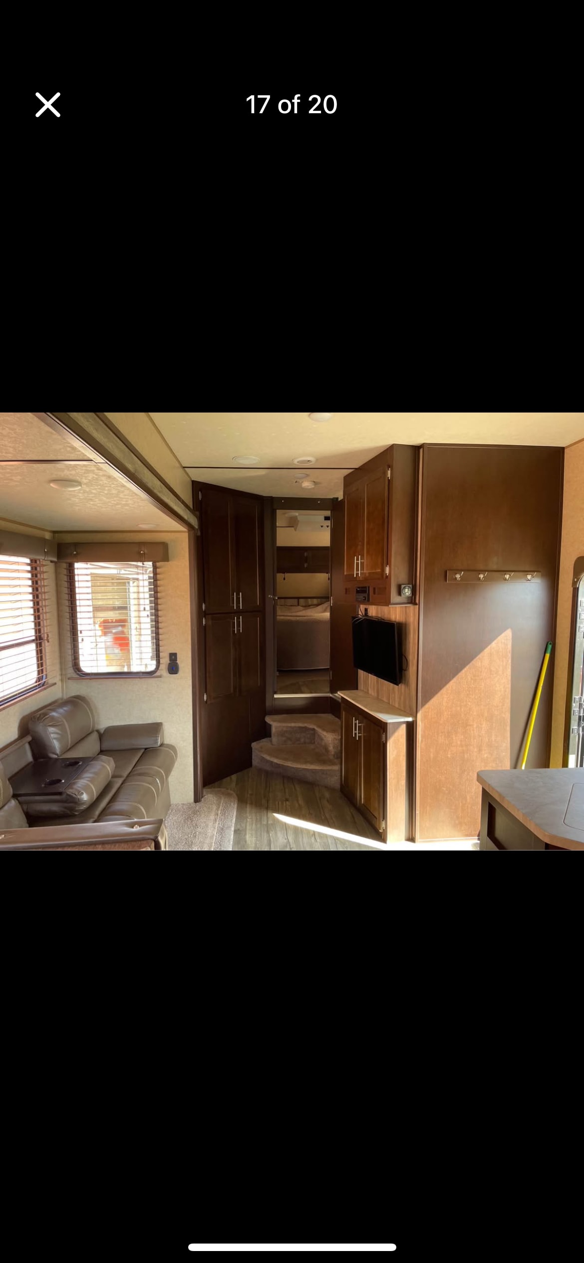 Spacious RV rental interior featuring a living area with sofa, wood floors, cabinetry, and steps to a bedroom.. Forest River Wolf Pack 2018