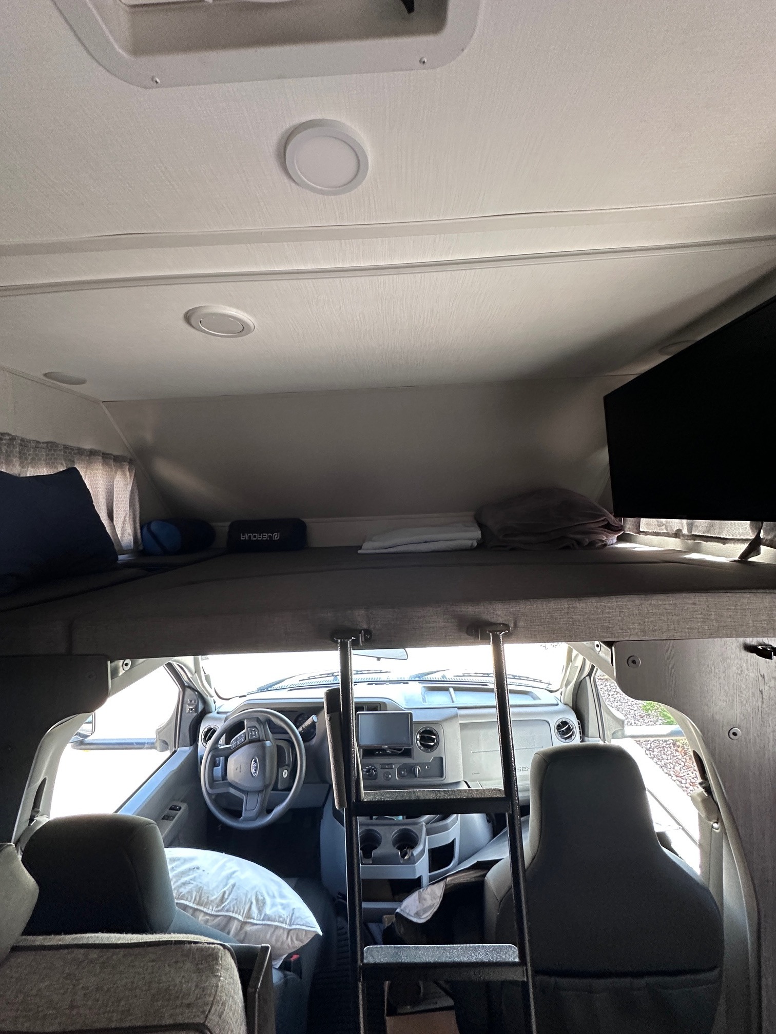 RV rental interior showing over-cab bunk bed, driver's cab, TV, and ladder. Ready for travel!. Forest River Sunseeker Classic 2021