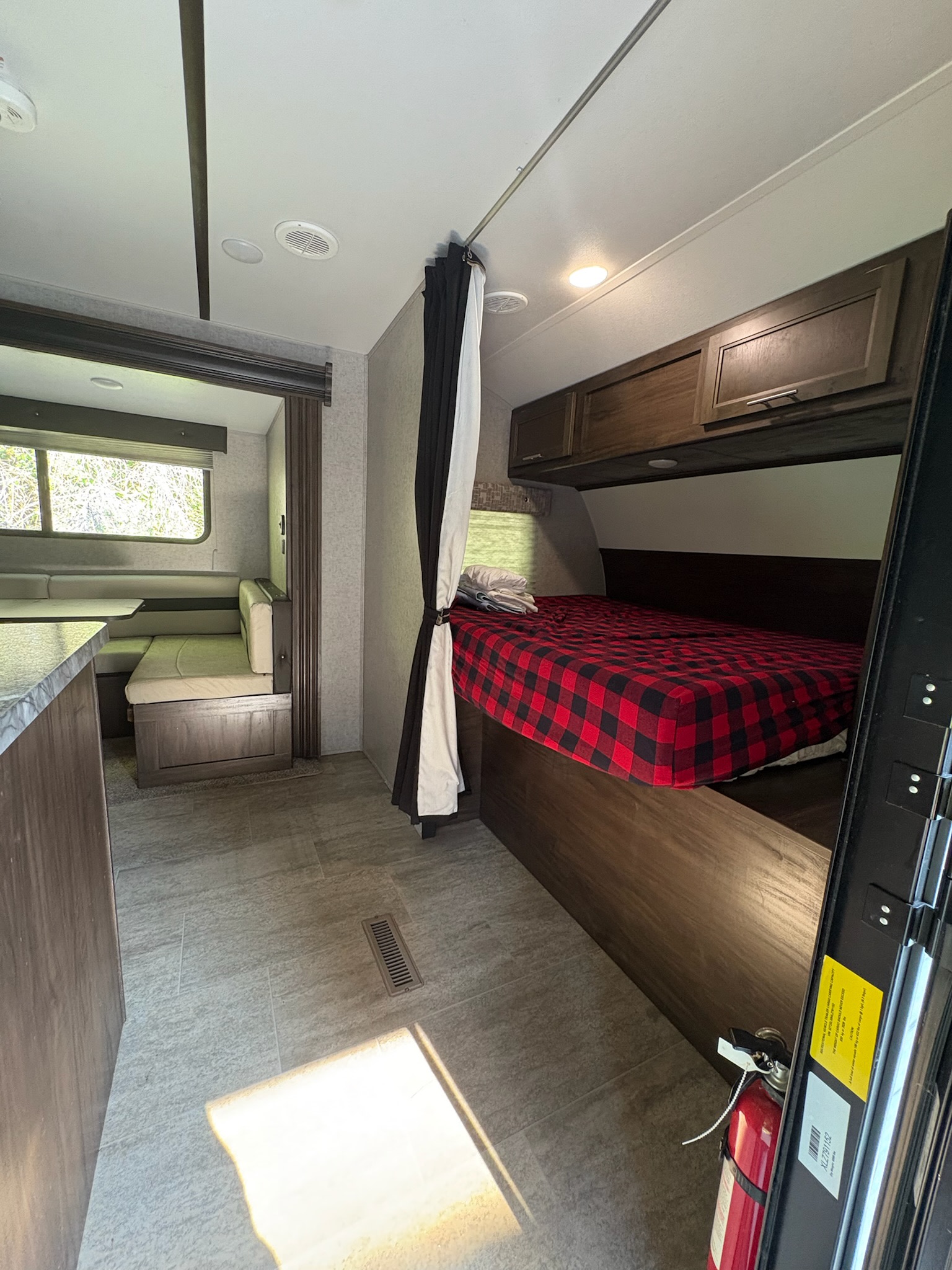RV rental interior: A cozy space with a red plaid bed, dining area, and kitchen counter visible.. Forest River Xlr Thunrderbolt 2020