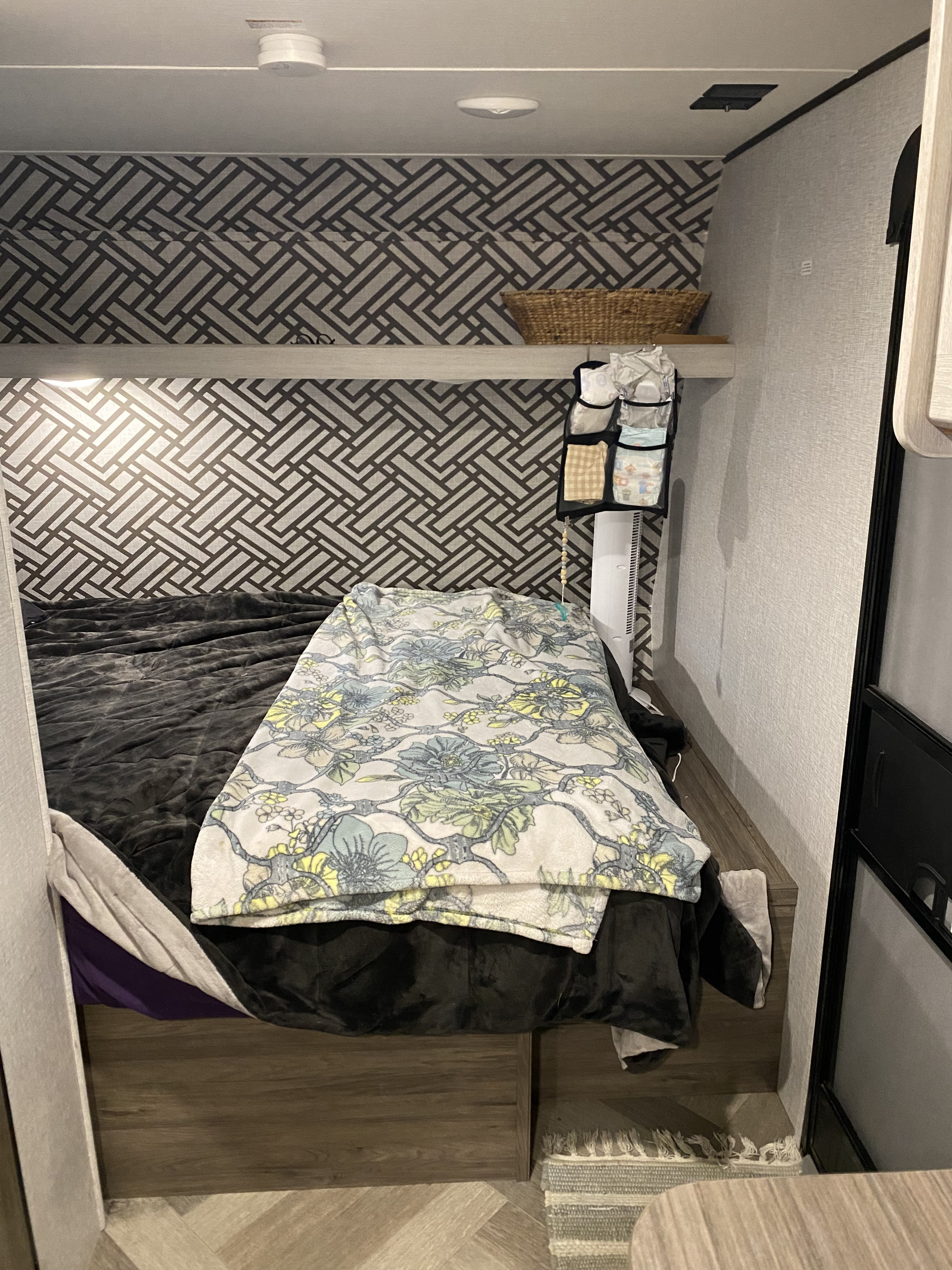 Cozy RV rental bunk bed with geometric wall, shelf, and baby essentials. Ideal for family travel.. Crossroads RV Crossroads Zinger 18QB 2024