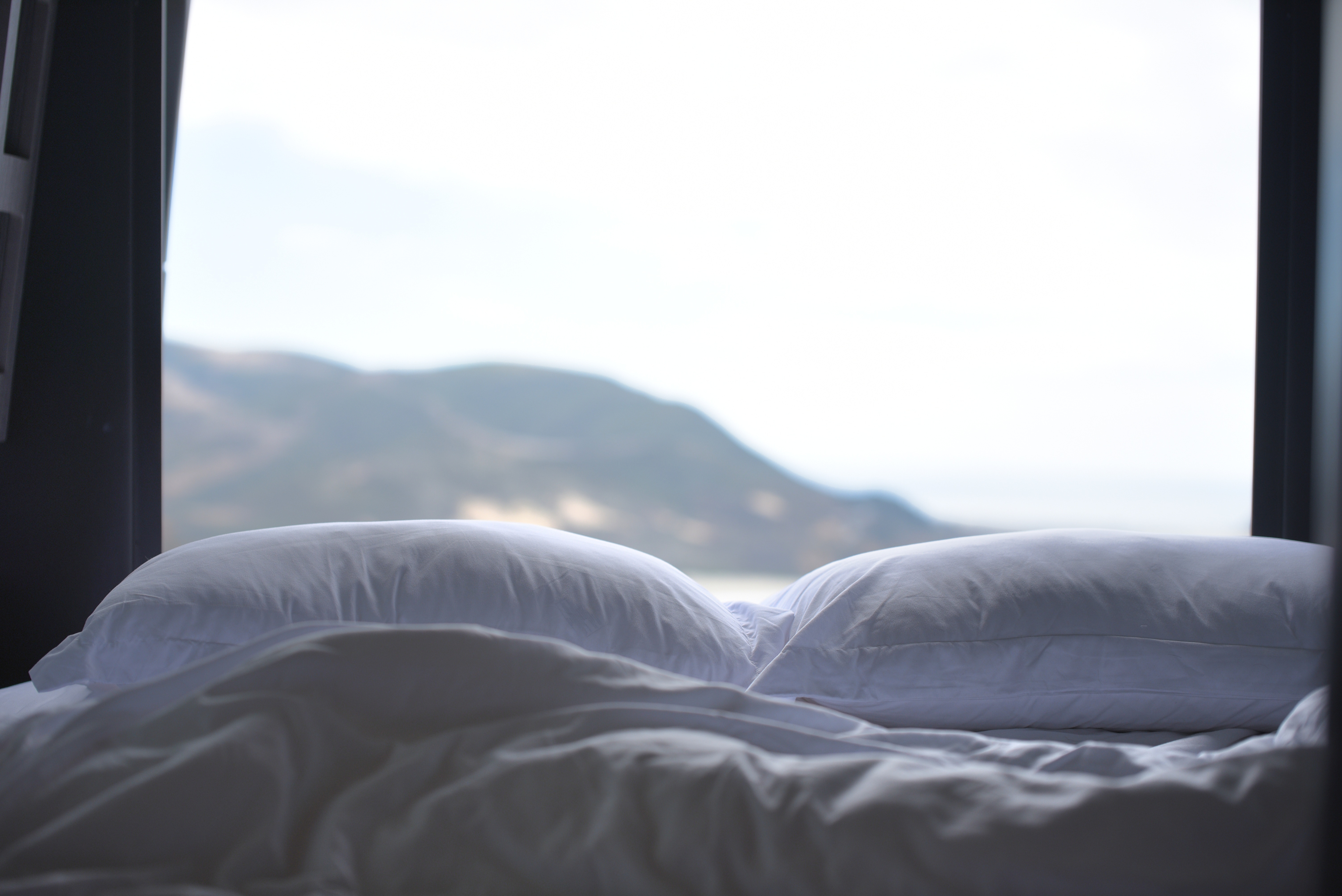 Cozy bed with white linens and a picturesque mountain view from your RV rental.. Grech RV Strada-ion 2024