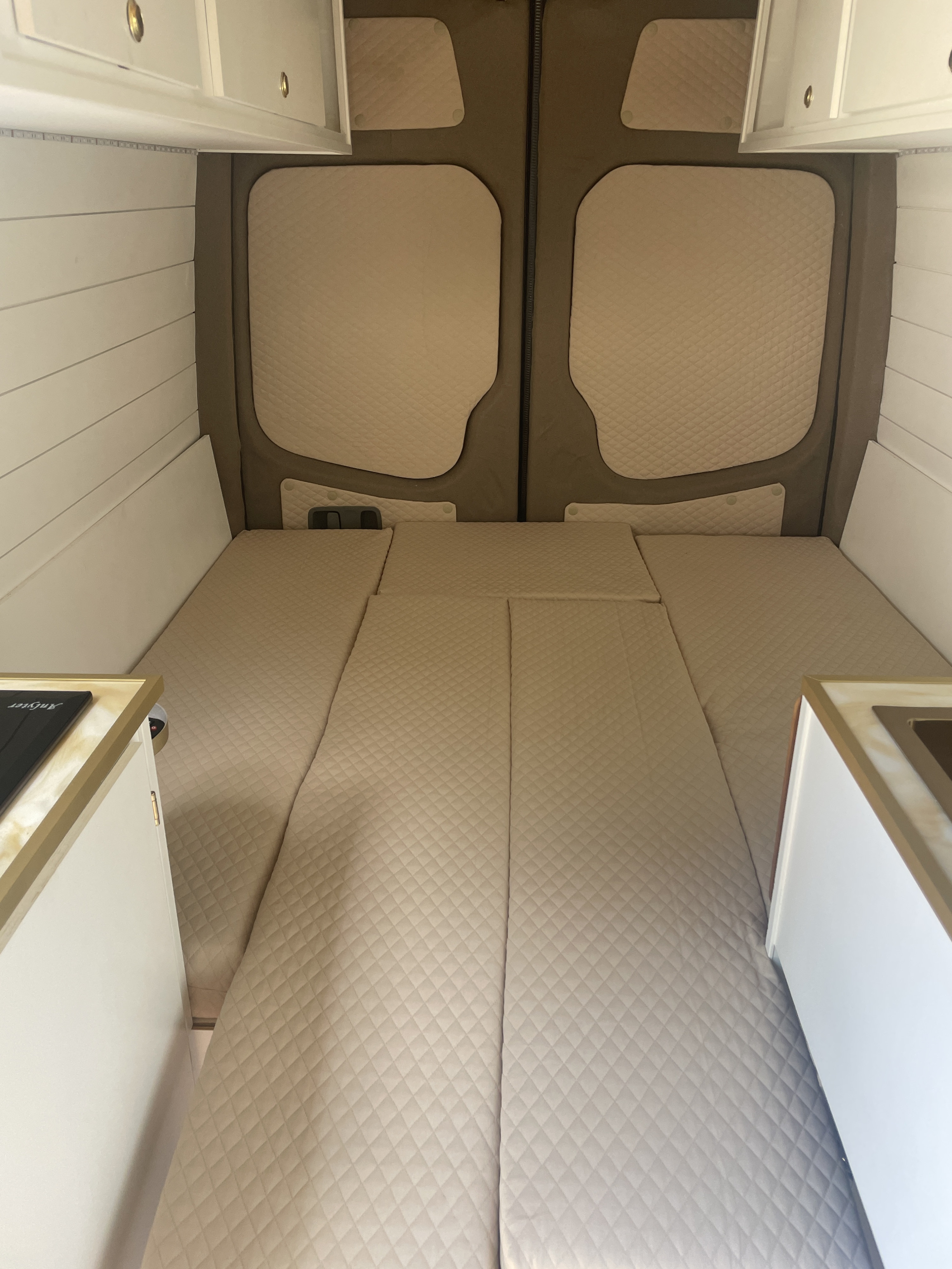 RV rental: Clean interior with a quilted bed, overhead storage, and compact kitchen setup.. Mercedes Sprinter 2013