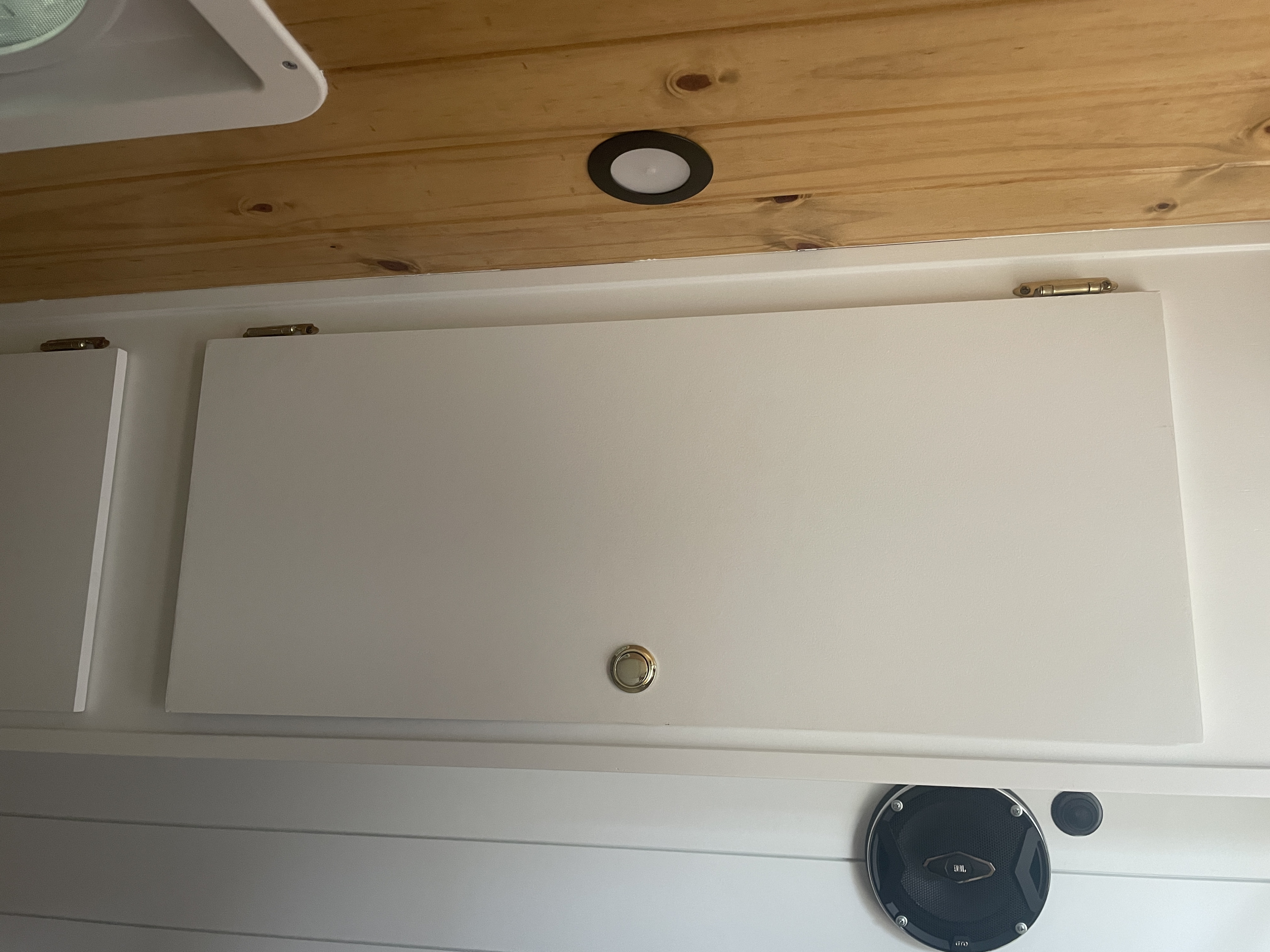 Inside an RV rental: Wood ceiling, white overhead cabinets with latches, and a JBL speaker enhance comfort.. Mercedes Sprinter 2013