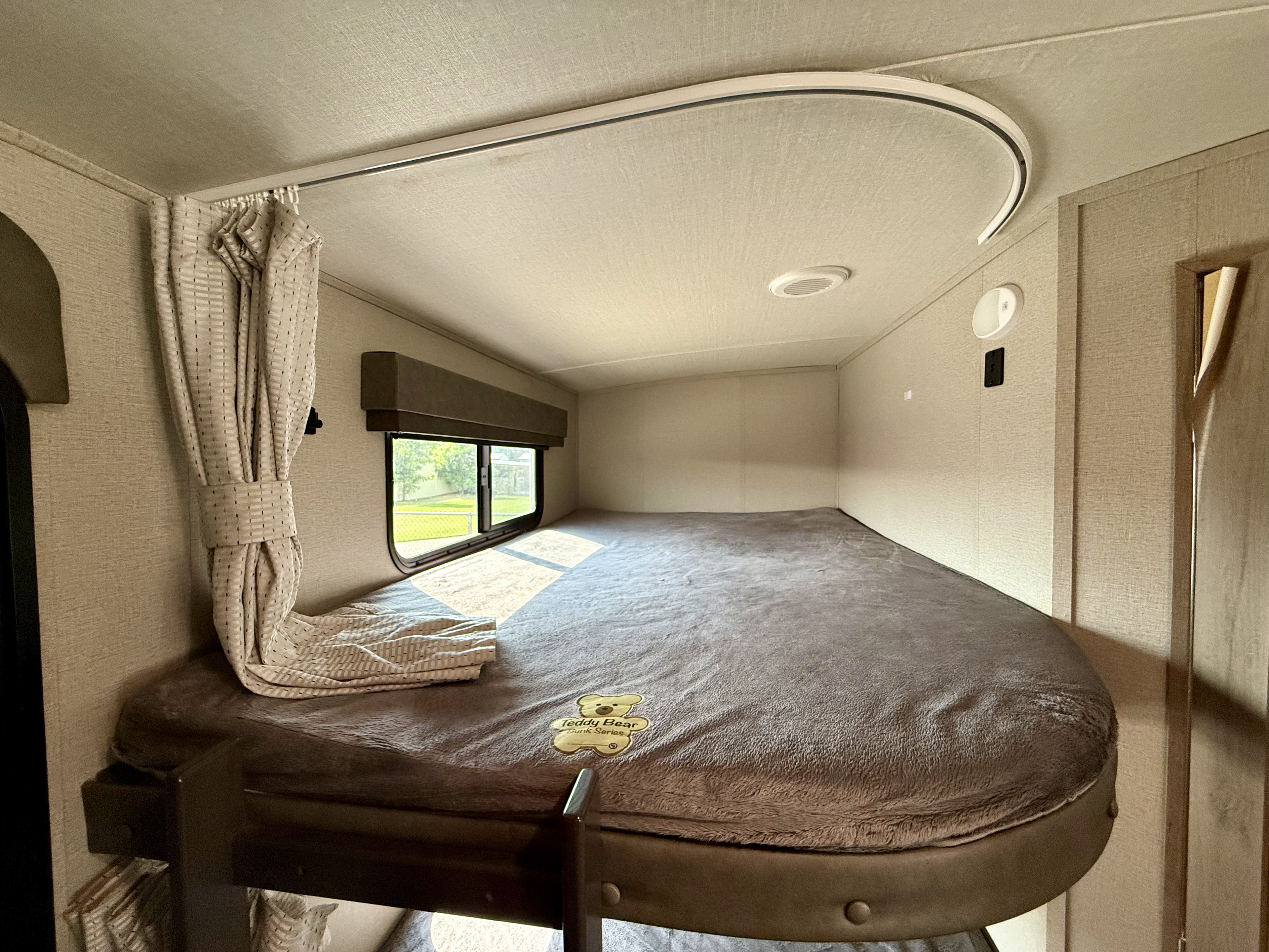 RV rental interior features a comfortable upper bunk bed with a window, privacy curtain, and soft mattress.. Grand Design Imagine 2021