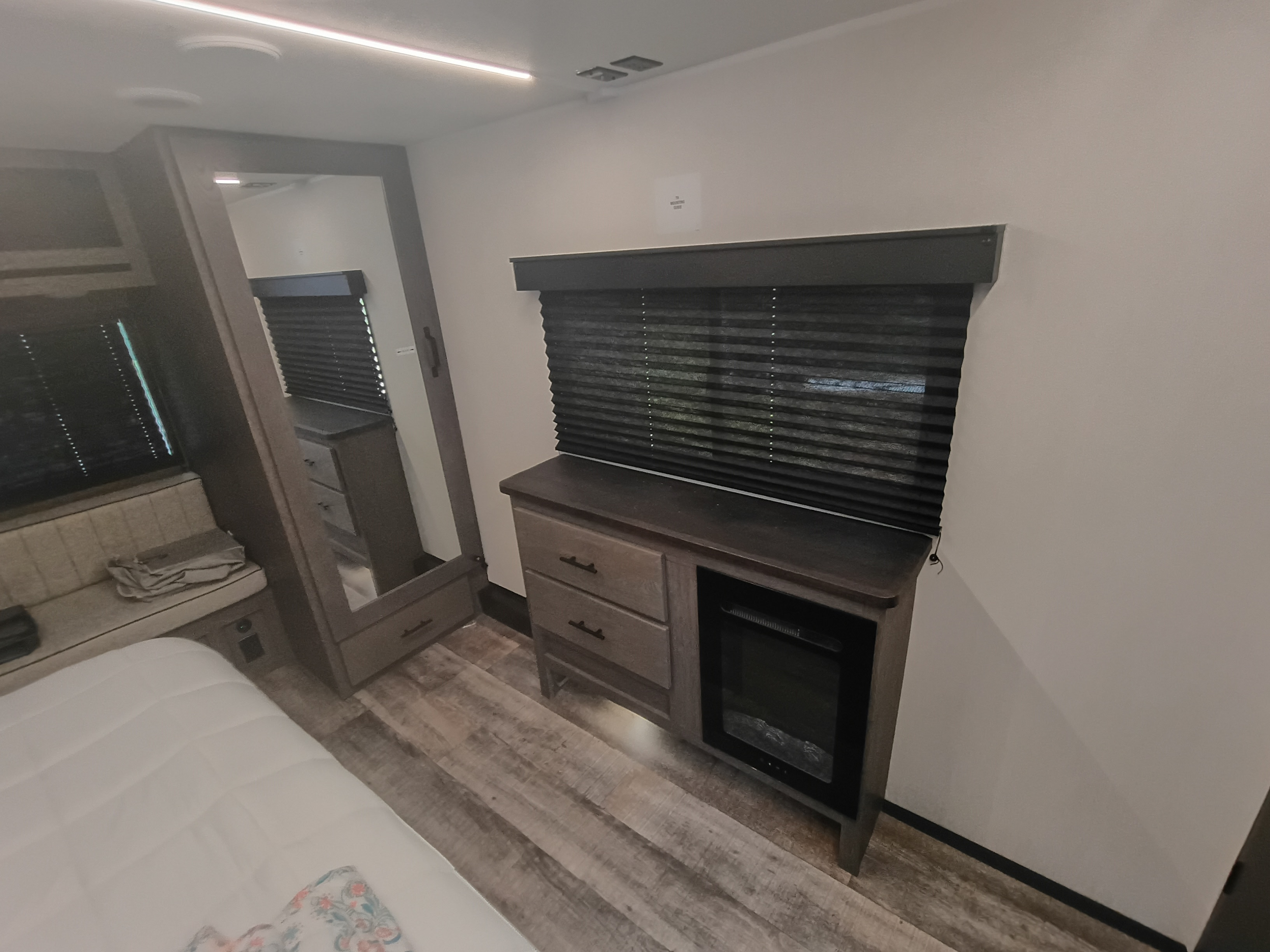 Comfortable RV rental interior: featuring a cozy bedroom with bed, mirrored wardrobe, and electric fireplace cabinetry.. Forest River Arctic Wolf 2025
