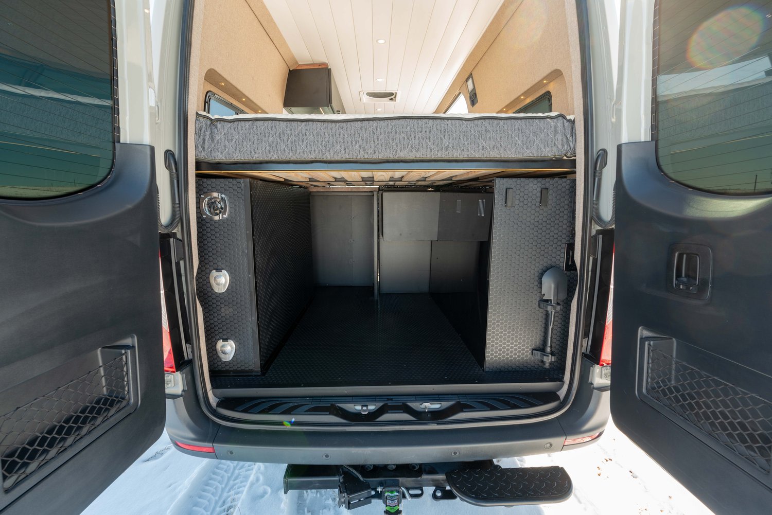 Explore an RV rental! This camper van features a comfy raised bed above a large, organized rear storage garage.. Mercedes-Benz Sprinter 2022