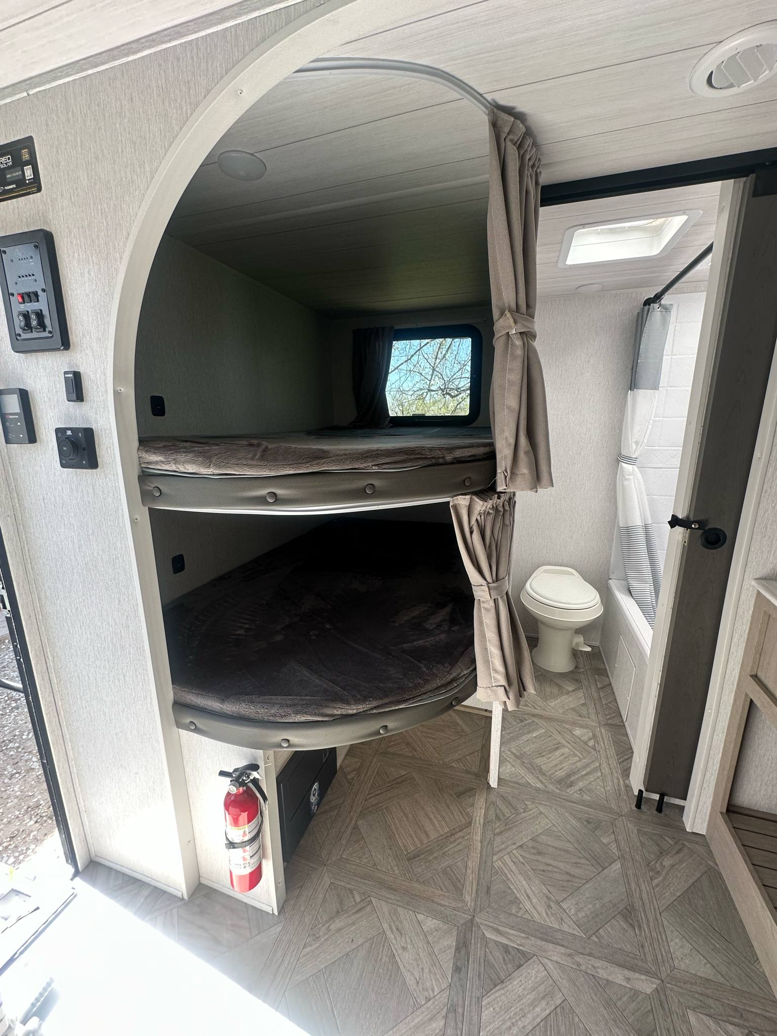 Cozy RV rental interior: bunk beds, compact bathroom, and controls. Ideal for family adventures.. Forest River Salem Cruise Lite 2024