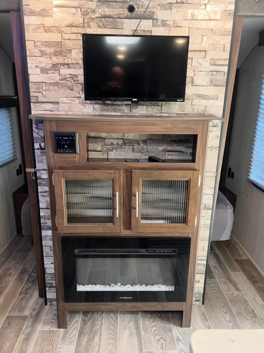 RV rental living area featuring a wall-mounted TV, integrated sound system, and an electric fireplace. Modern rustic interior design.. Forest River Cherokee Grey Wolf 2019