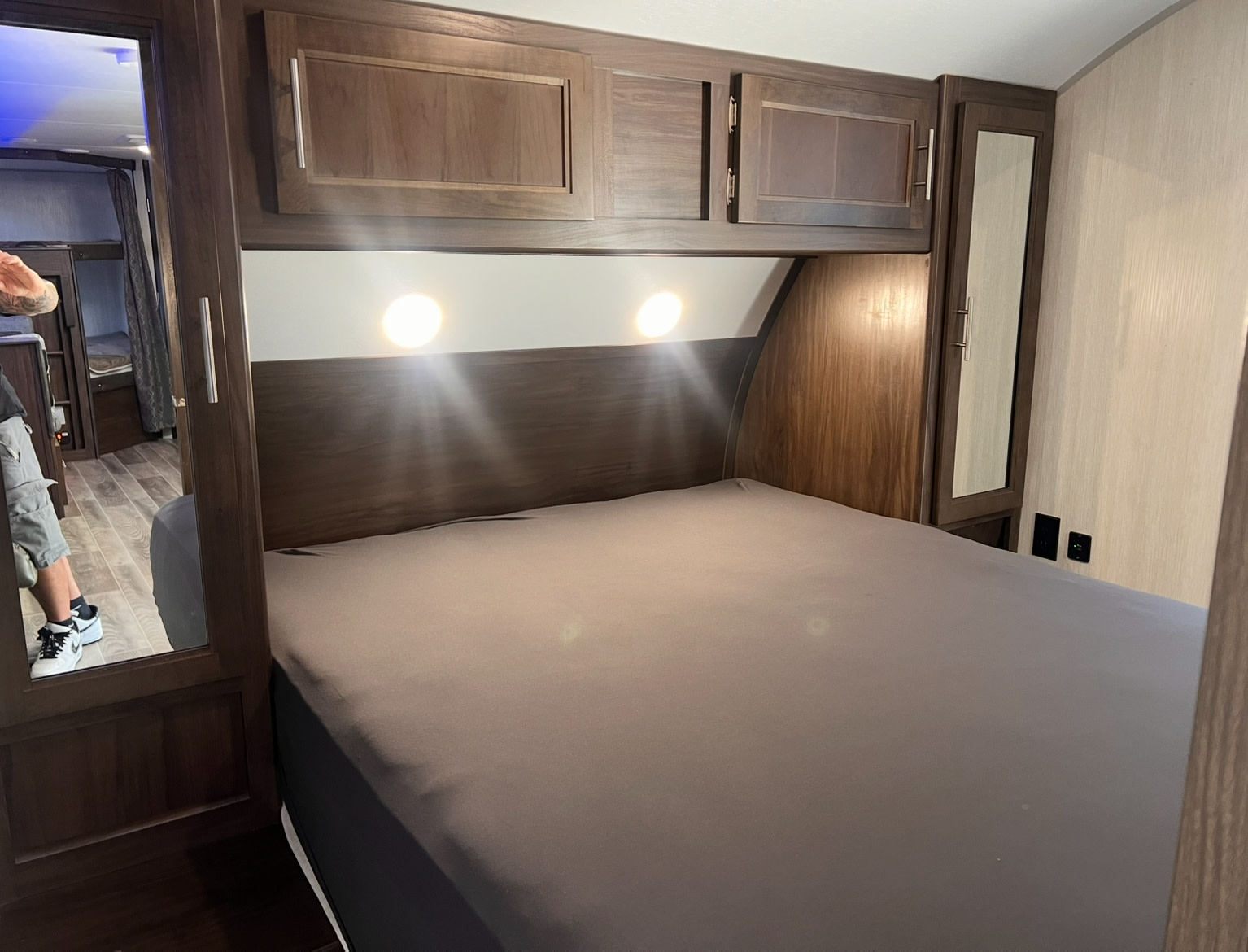 This RV rental bedroom features a comfortable bed, overhead cabinets, bright lights, and a mirrored closet.. Forest River Cherokee Grey Wolf 2019