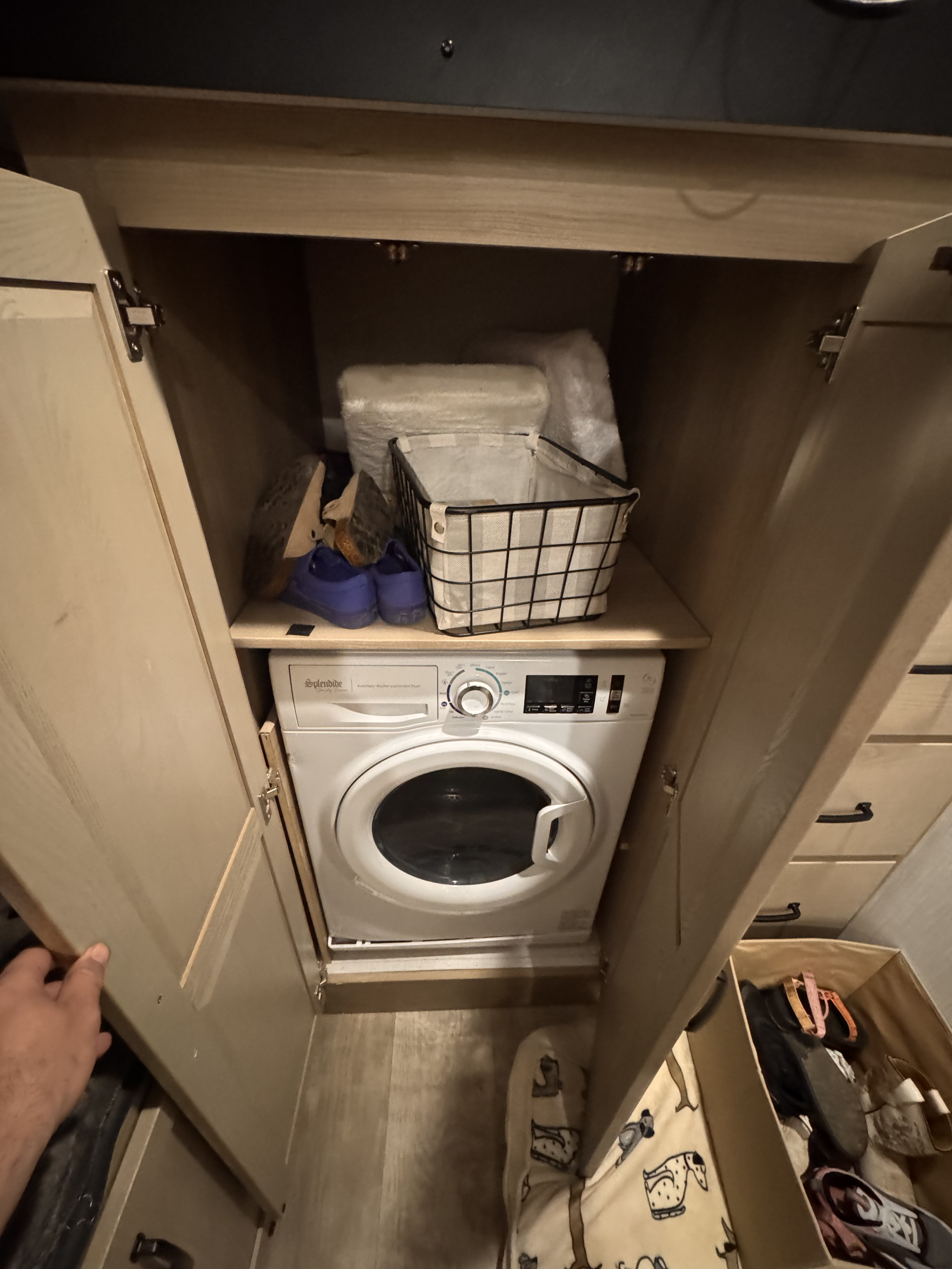 RV rental: Compact Splendide washer/dryer unit installed in a small closet with an upper shelf for shoes and a basket.. Forest River Rockwood Signature 2024
