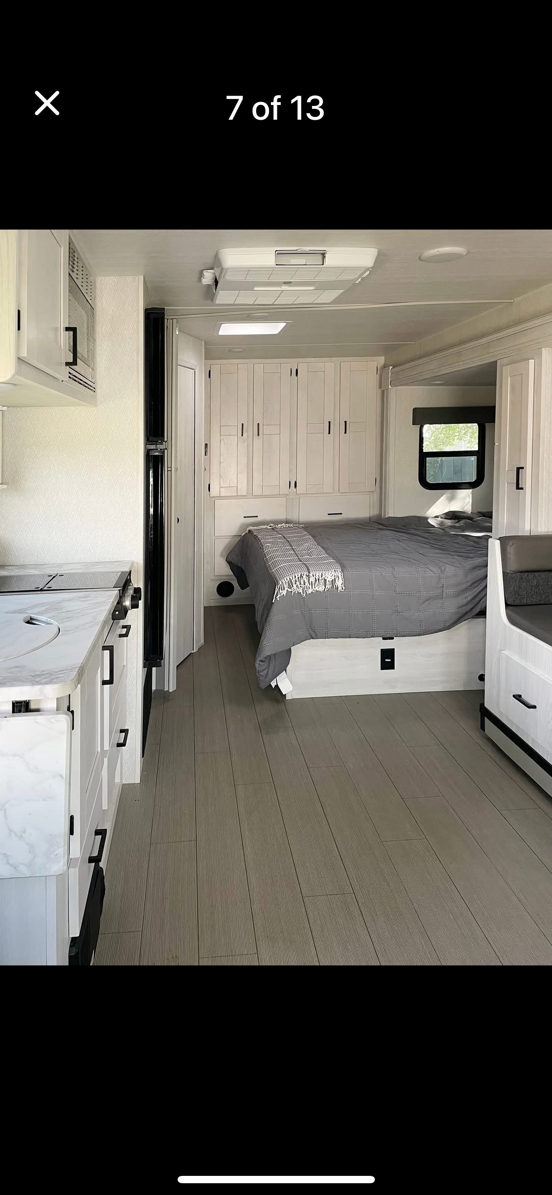 Spacious RV rental interior featuring a modern kitchen, comfortable bedroom with built-in storage, and light wood-look flooring.. east to west entrada 2023