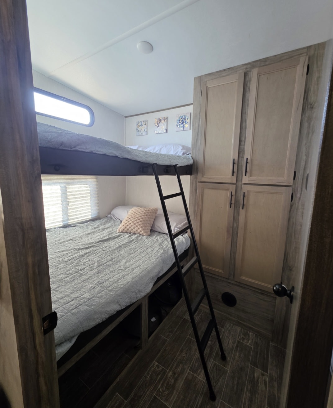 Cozy RV rental interior features comfortable bunk beds with a ladder, window blinds, & storage cabinets. Ideal for family camping.. Forest River Cherokee Arctic Wolf 2021