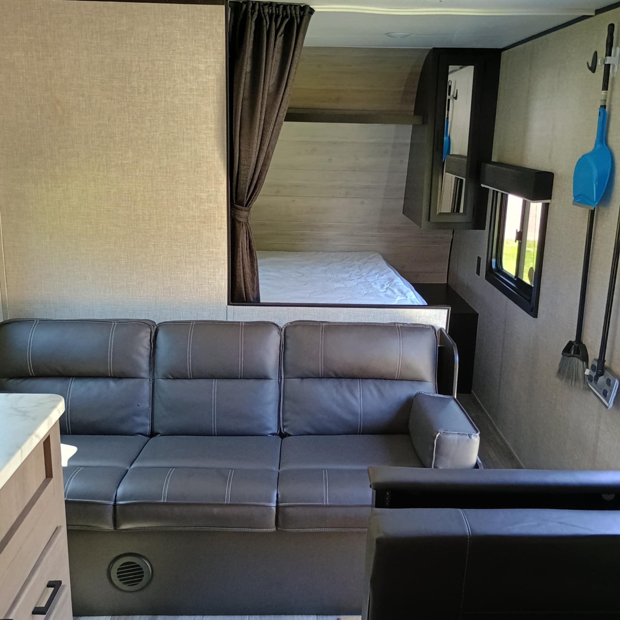 Cozy RV rental interior featuring a comfortable gray sofa, private bunk bed, and essential amenities for your adventures.. Jayco Jay Flight SLX 2022