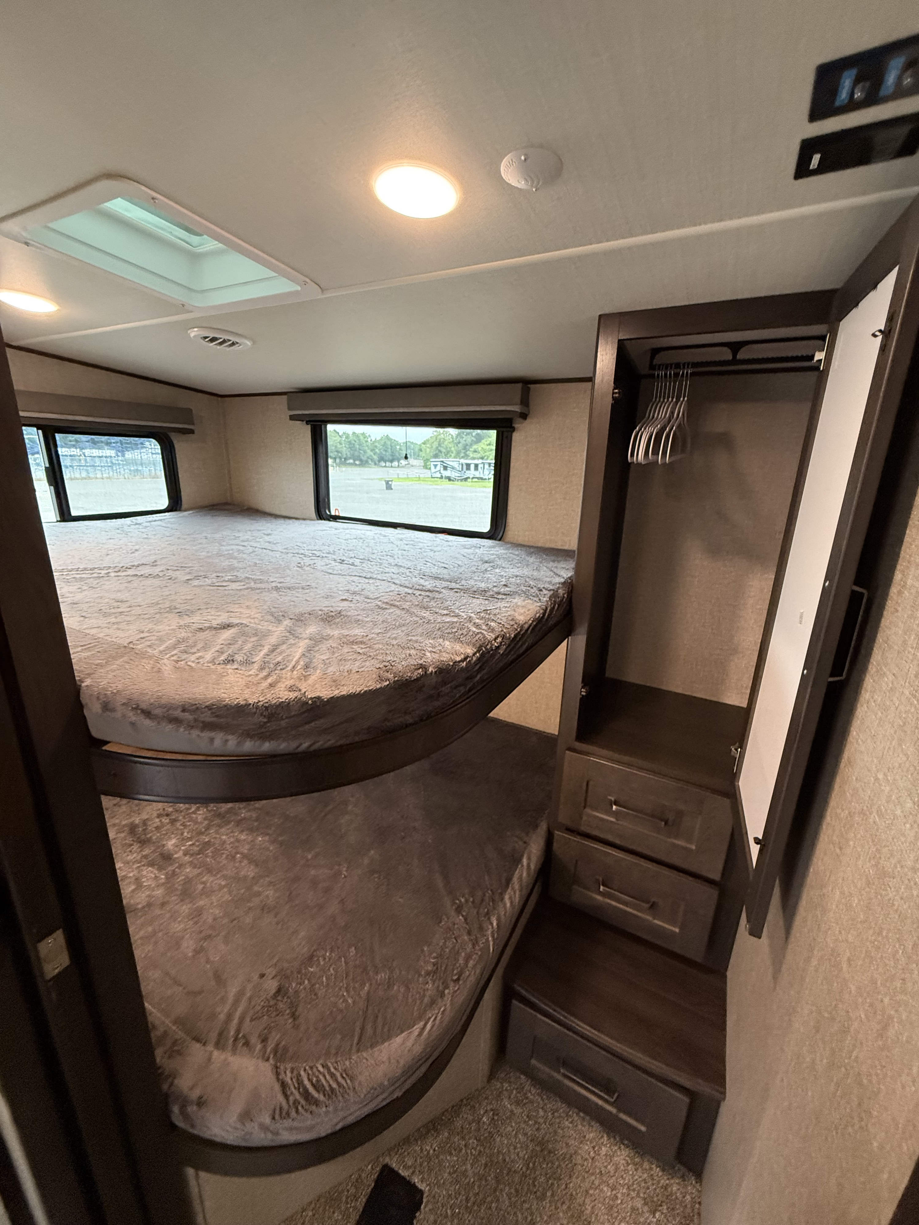 Experience comfort in this RV rental's bedroom featuring cozy bunk beds, a skylight, and built-in storage.. Grand Design Reflection 2022