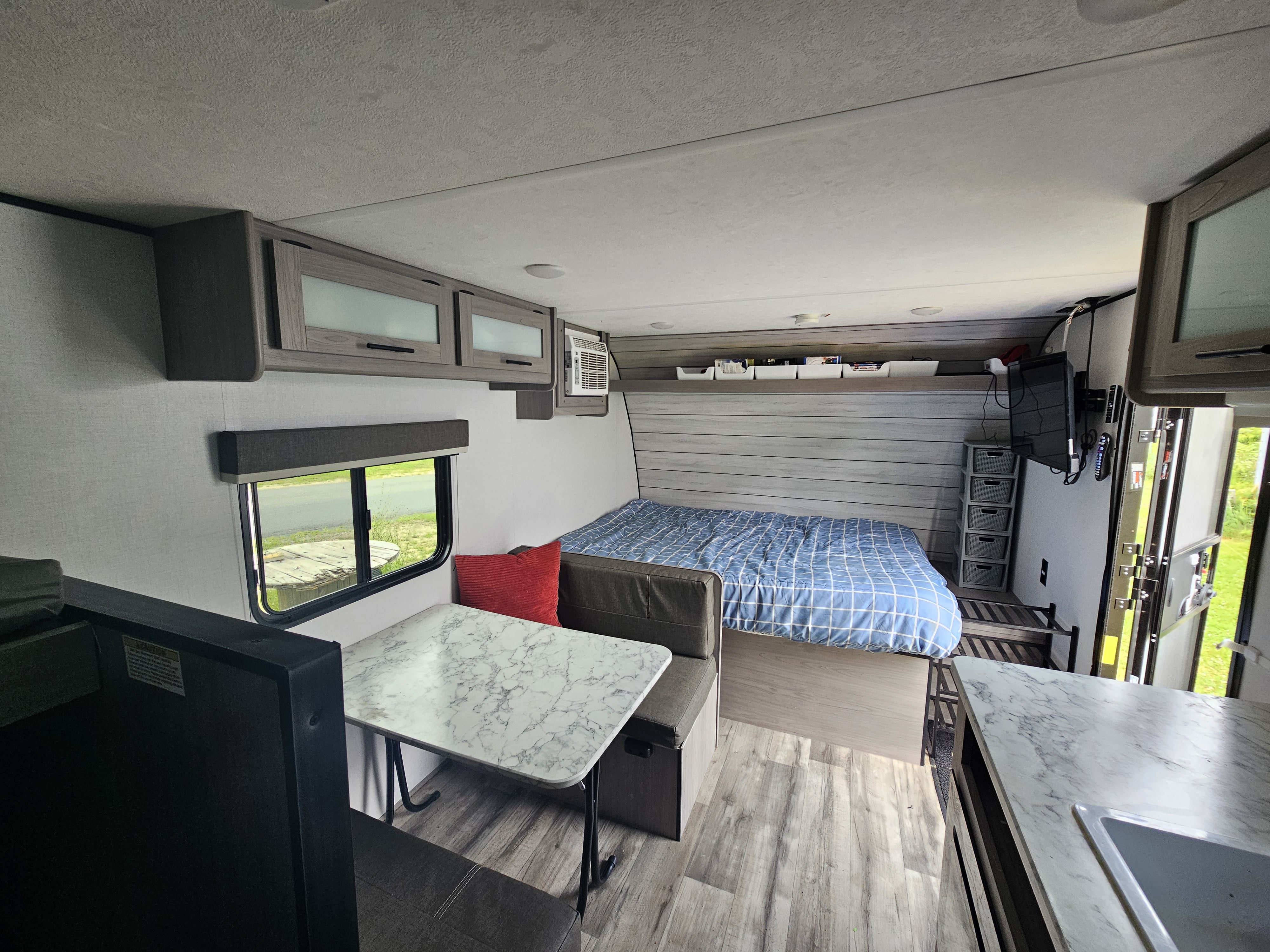Cozy RV rental interior featuring a bed, dining area, and kitchen counter – perfect for your next adventure.. Coleman 17b 2024