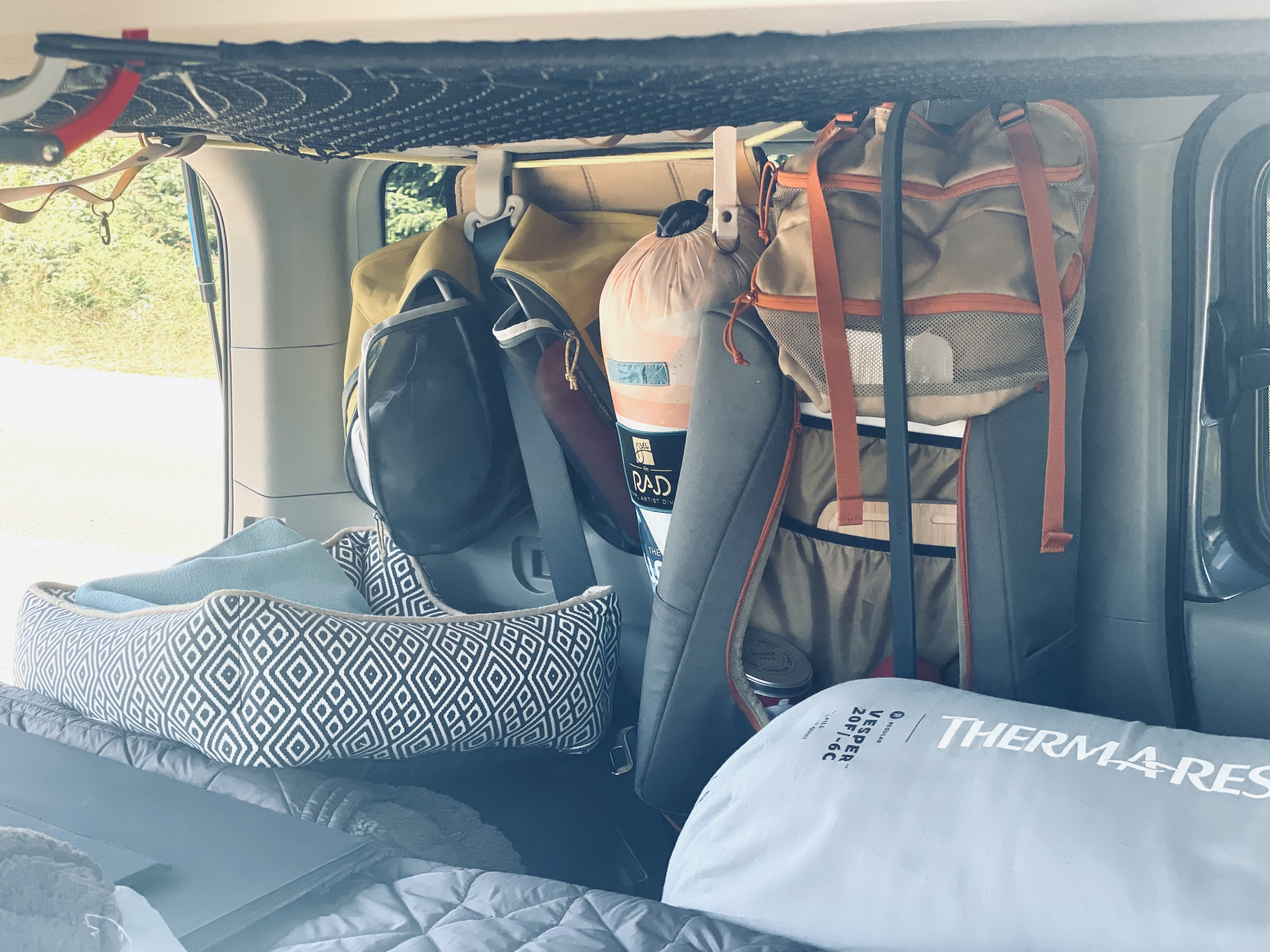 An RV rental's clever storage: overhead net, hanging bags, a dog bed, and a Therma-Rest sleeping quilt.. Honda Element EX 4WD 2010