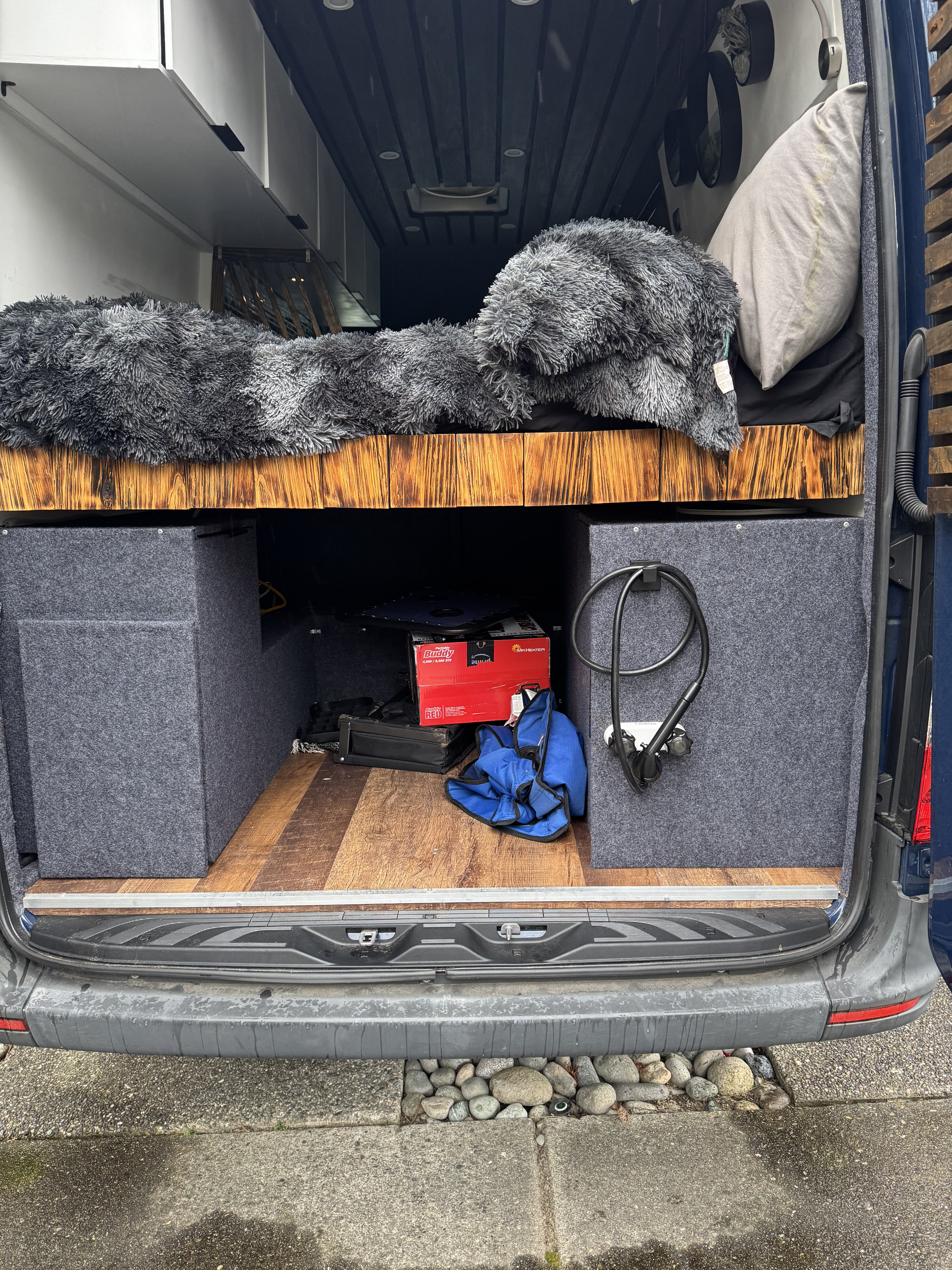 Rear view of an RV rental: a plush bed, under-bed storage boxes, and wood flooring for comfortable travel.. Mercedes-Benz Sprinter 2020