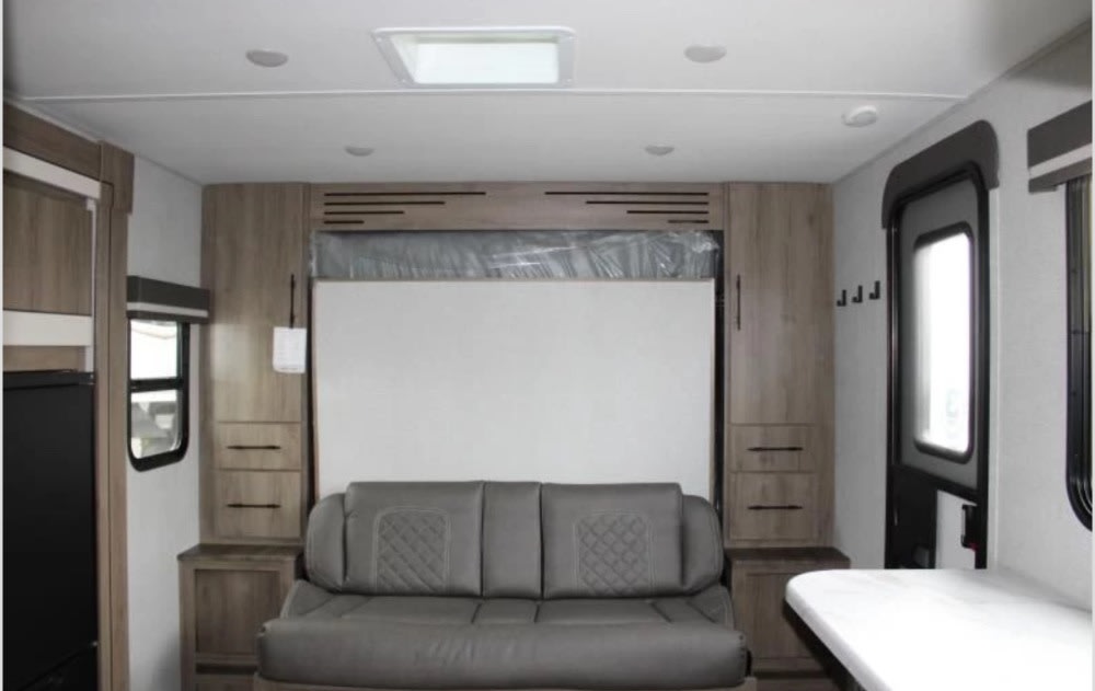 Clean RV rental interior featuring sofa, pull-down bed, cabinets, and a dinette. Ready for travel!. Grand Design Imagine AIM 2023
