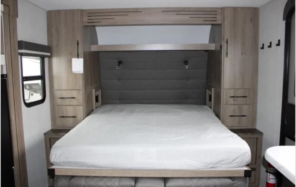 RV rental bedroom: Cozy, compact sleeping area with queen bed, overhead storage, and reading lights.. Grand Design Imagine AIM 2023