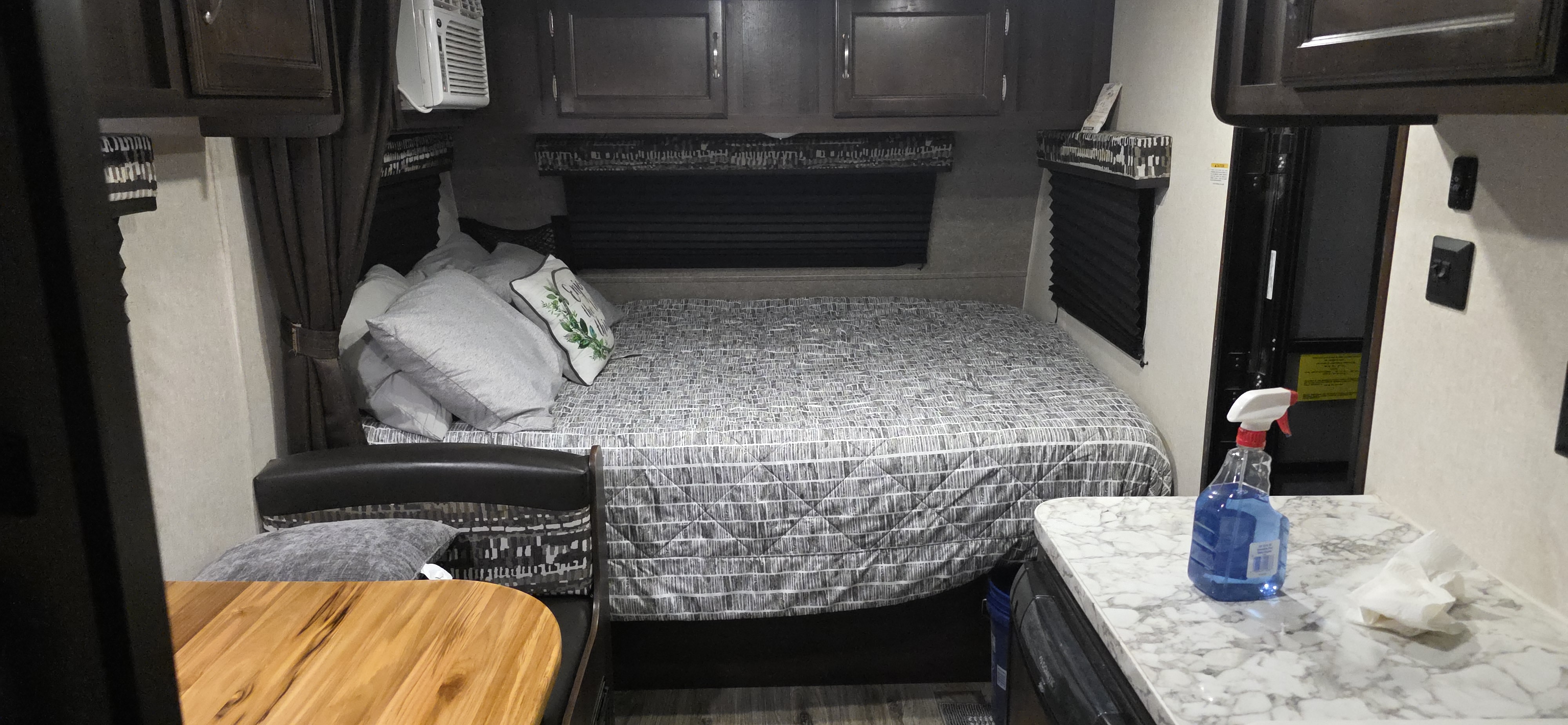 Experience an RV rental's cozy interior, featuring a compact bedroom with a patterned bed, overhead cabinets, and a small side counter.. Jayco Jay Flight SLX 2018