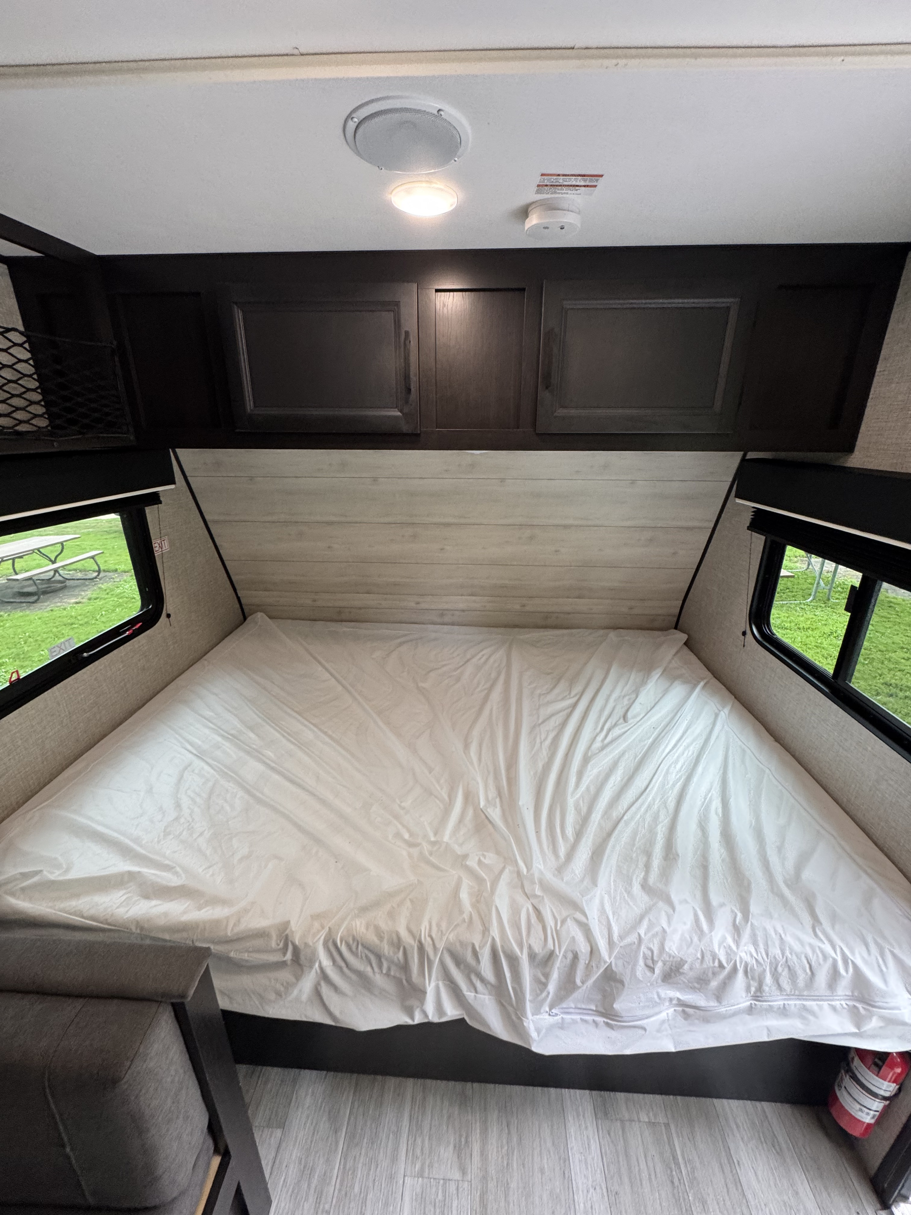 RV rental bedroom: cozy space with large bed, white covering, overhead storage. Windows offer campsite views.. Jayco Jay Flight SLX STX Edition 2022