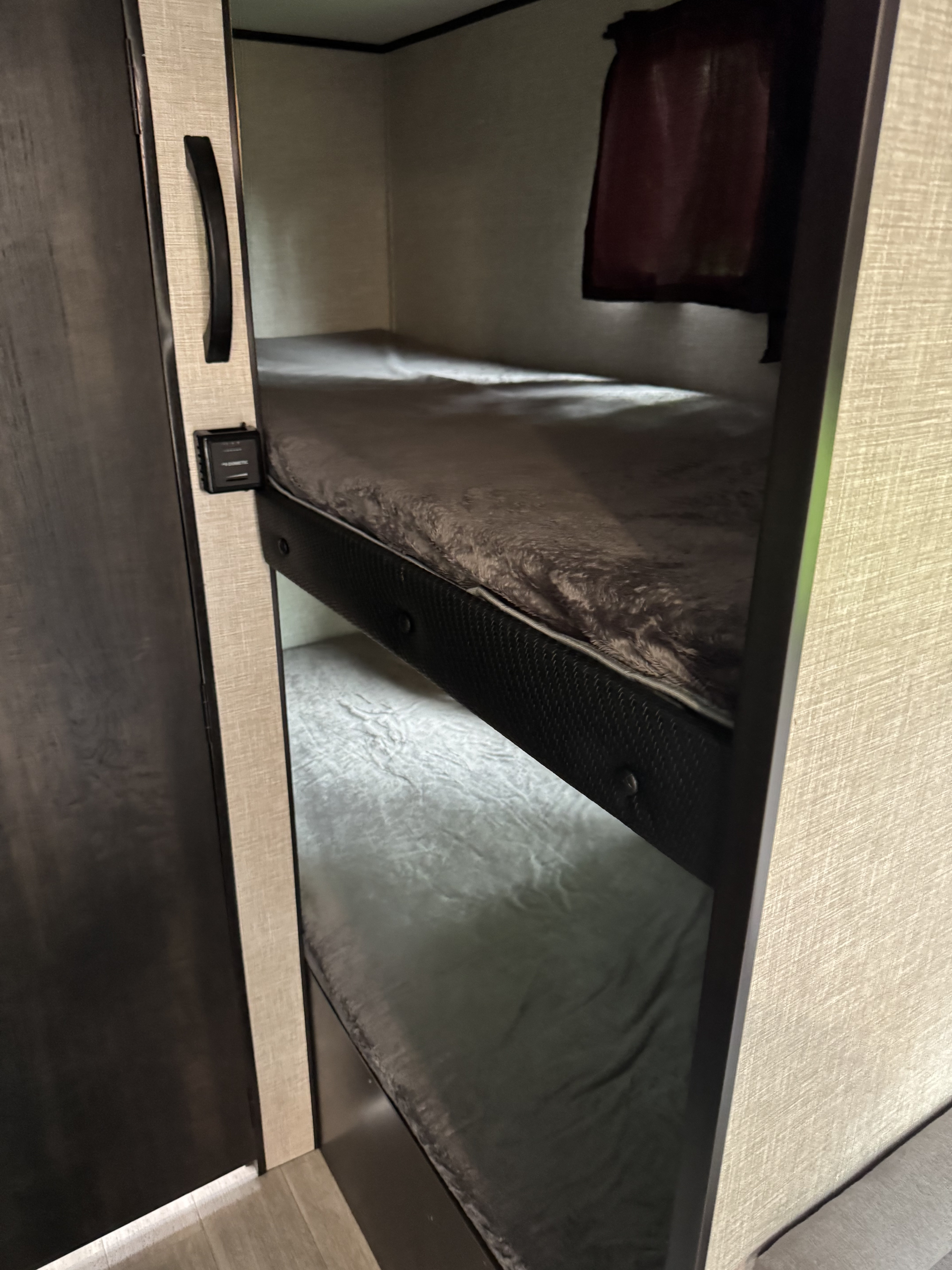 An RV rental's cozy bunk beds with soft gray bedding provide compact sleeping for travel adventures.. Jayco Jay Flight SLX STX Edition 2022