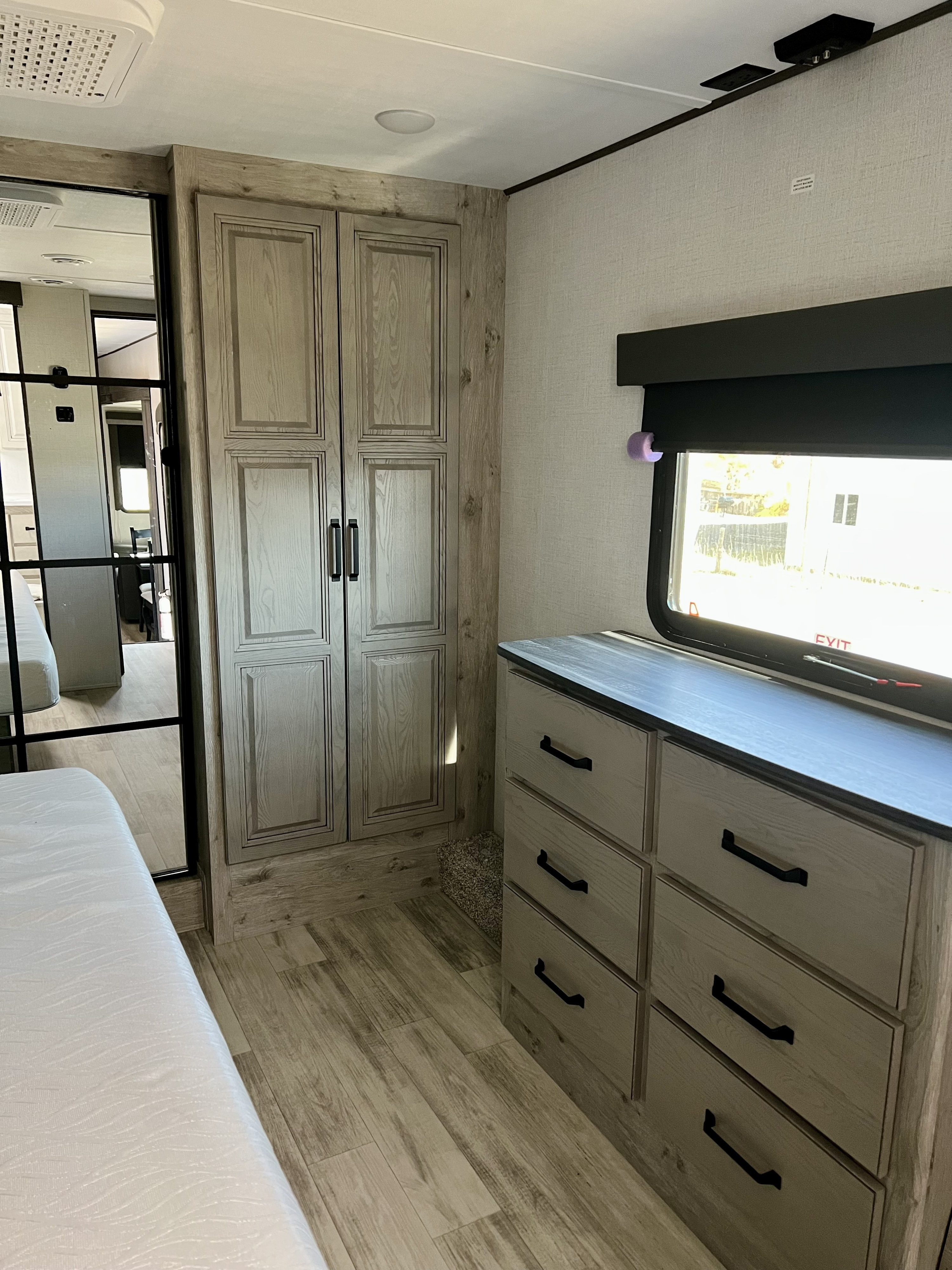RV rental bedroom: light wood cabinets, dresser, bed, and window. Modern and functional interior for your travels.. Keystone RV Alpine Avalanche 2024