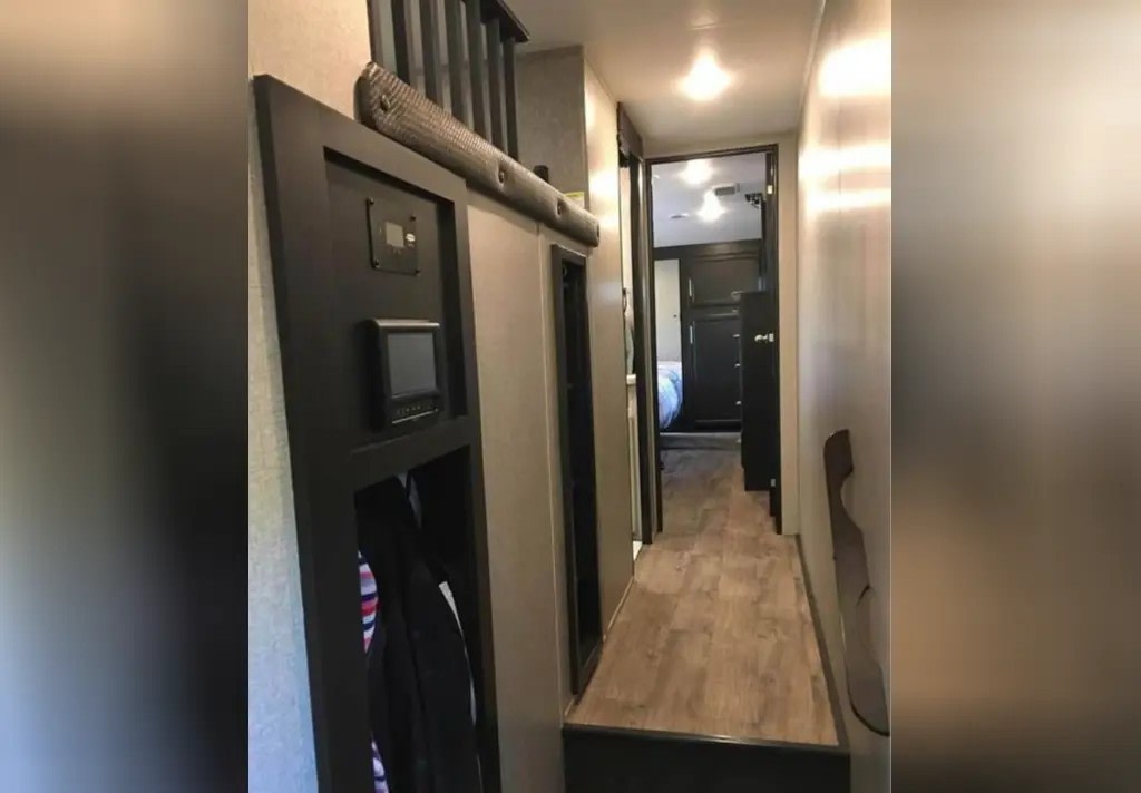 Interior of an RV rental: a modern hallway with a control panel, coat storage, and a bedroom visible in the distance.. Jayco Eagle 2021