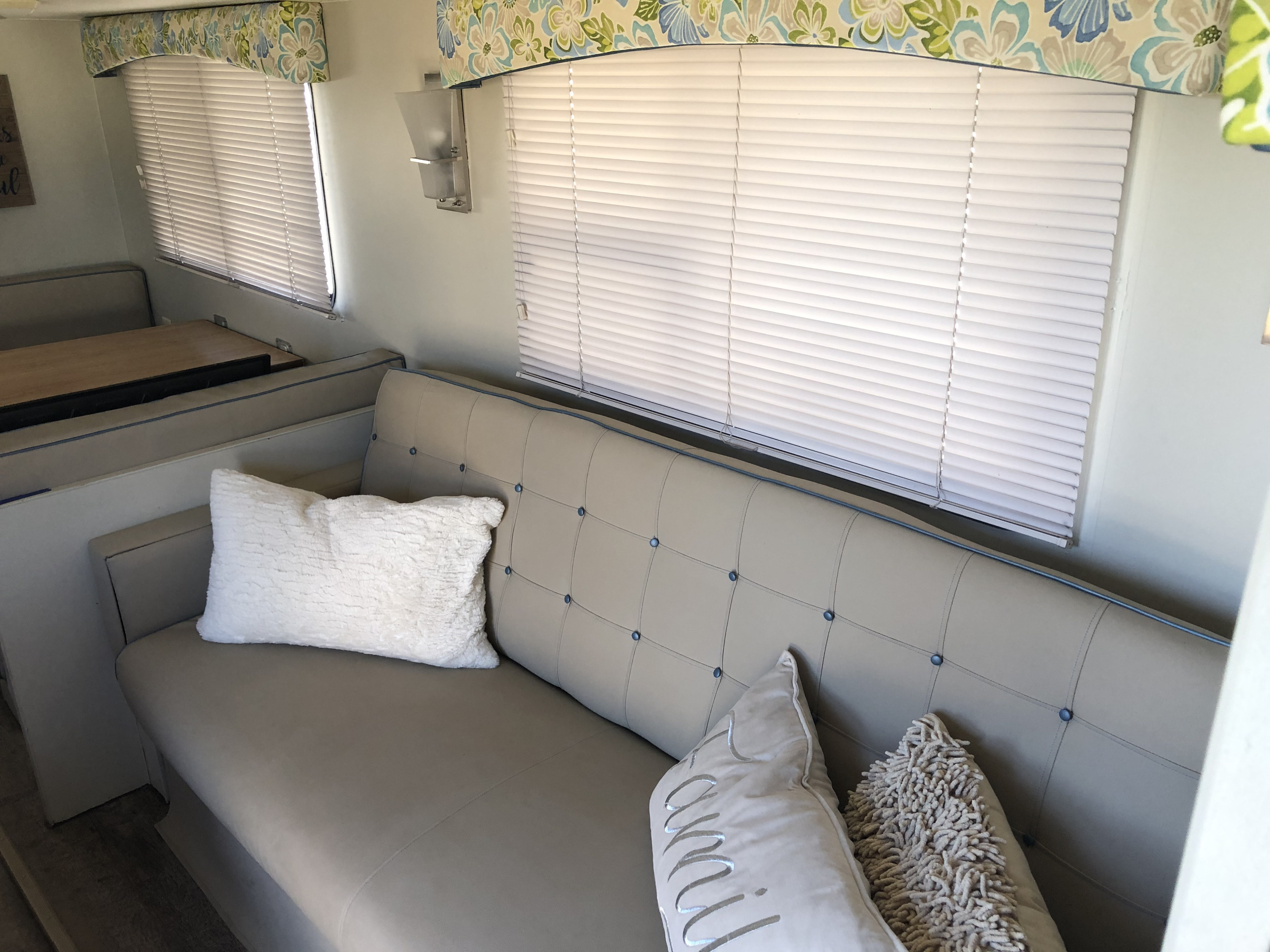 Comfortable RV rental with a light grey tufted sofa, plush pillows, and dining area.. Fleetwood Wilderness 1997