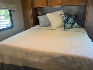 Comfortable RV rental bedroom with white bedding & decorative pillows. Ideal for your next road trip.. Fleetwood Wilderness 1997