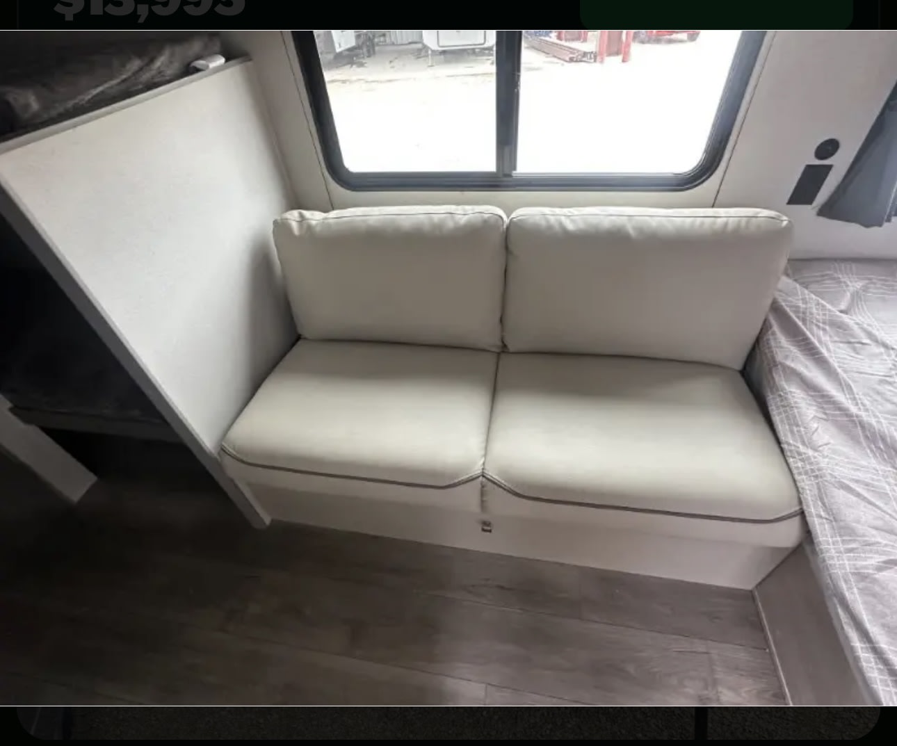 Cozy RV rental interior with a light two-seat sofa by a large window, wood-look floor, and comfortable living space.. Coachman Catalina 164BHX 2025