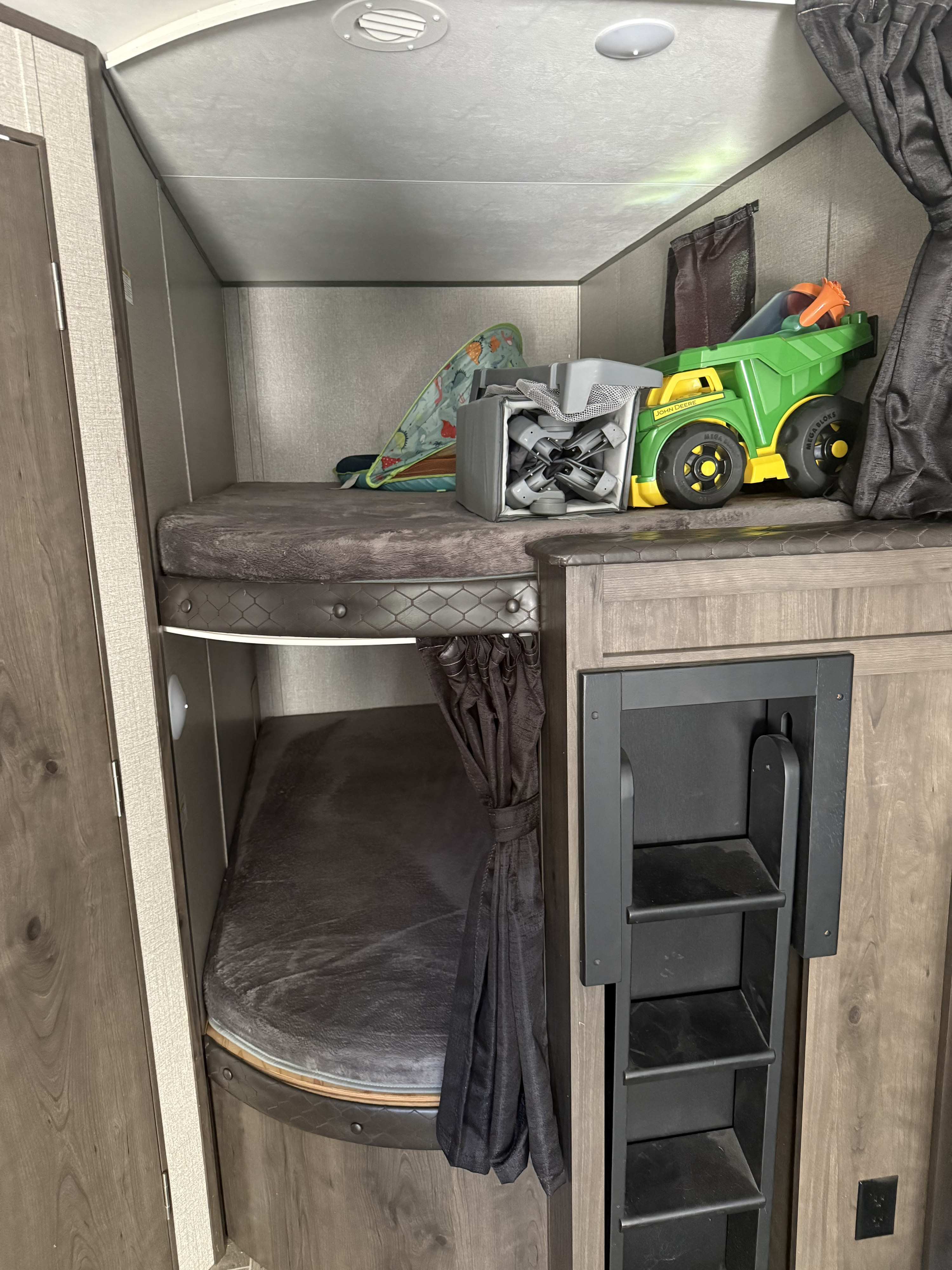 RV rental's bunk beds: top with toys, bottom with privacy curtain, and a built-in ladder for access.. Jayco Jay Flight 2022