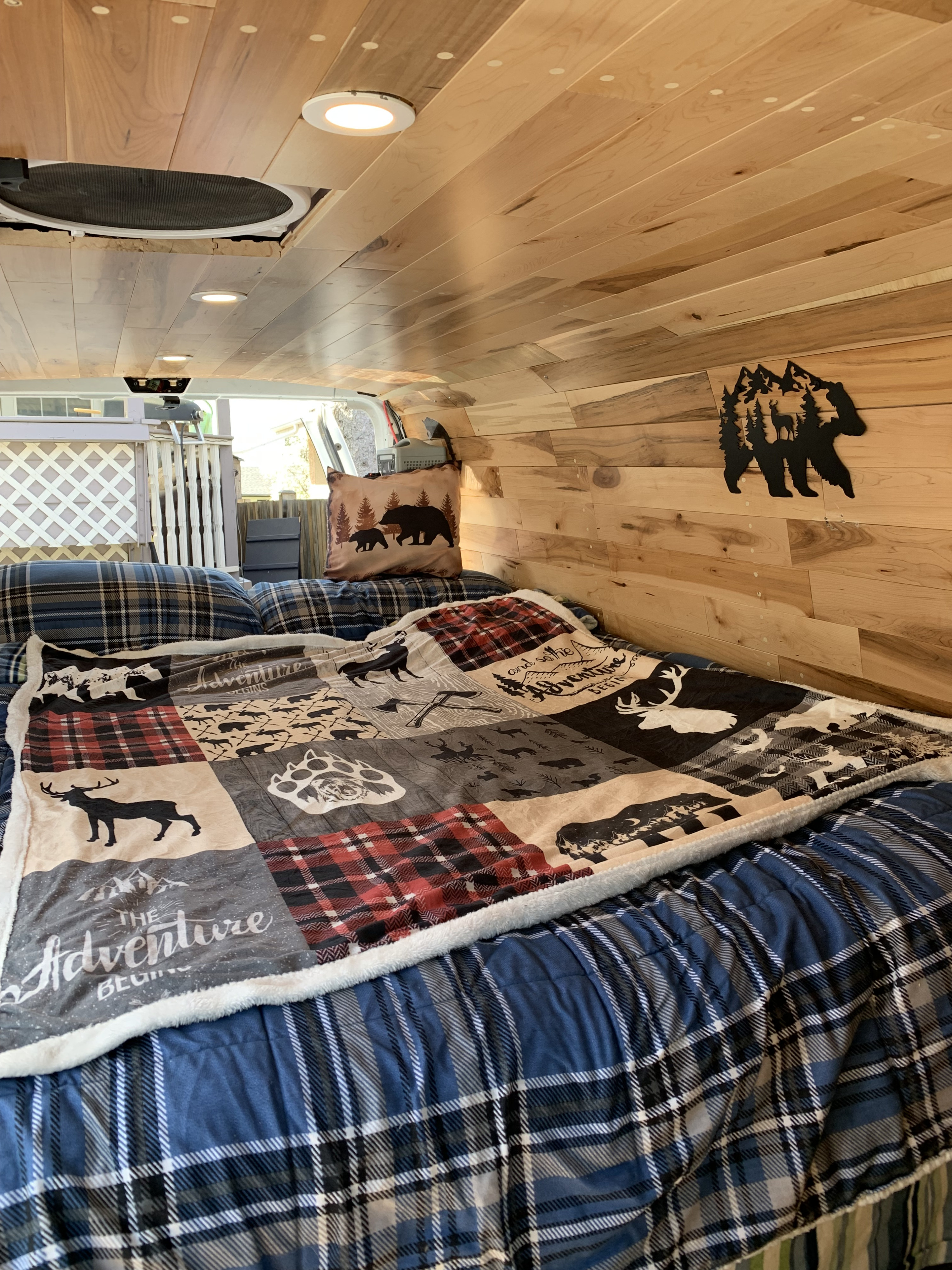 Cozy RV rental bedroom with rustic wooden walls, plaid bedding, and nature-themed decor.. Ford Econoline E250supercab 2010