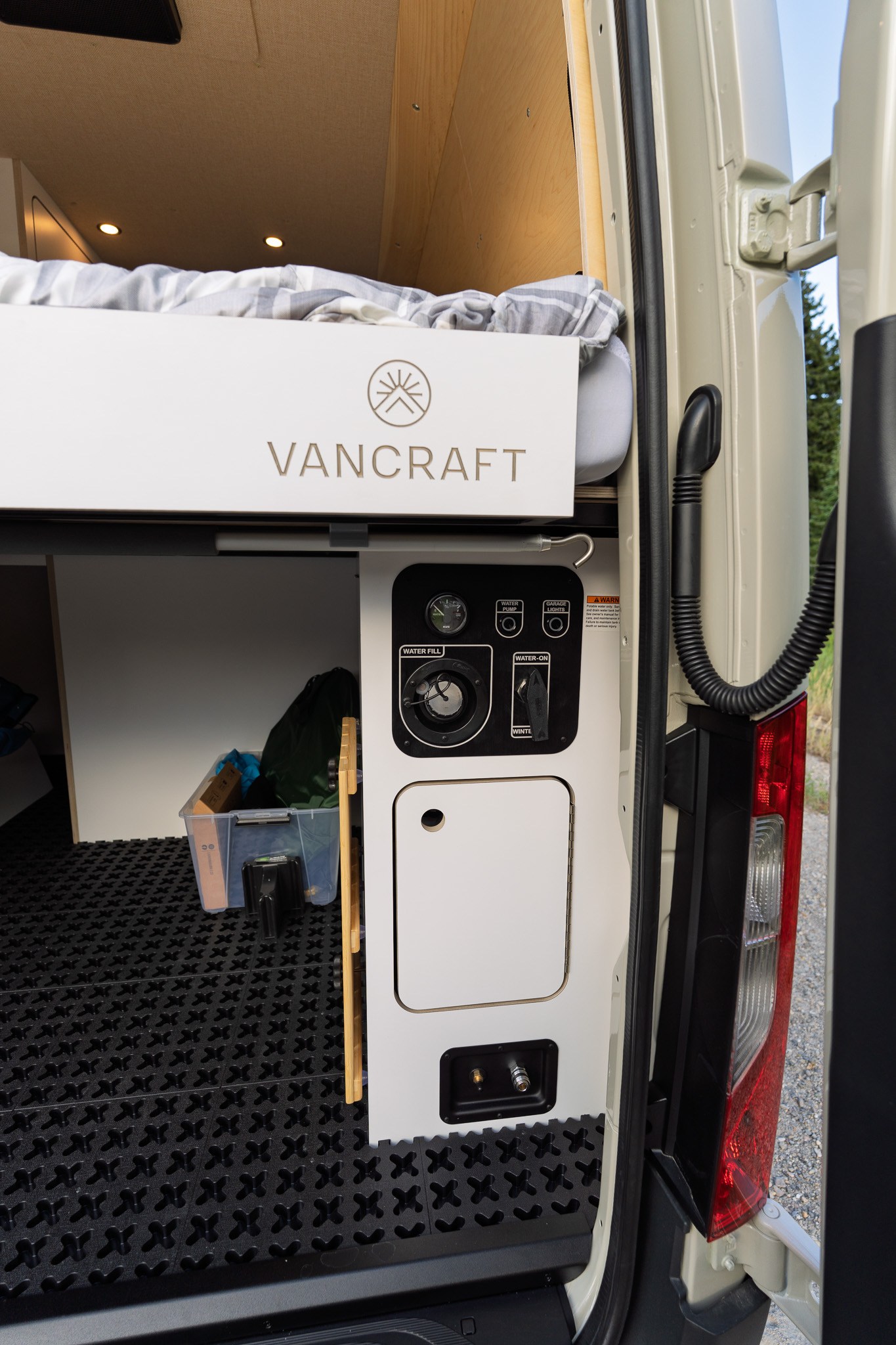 Explore the rear of this custom Vancraft RV rental, featuring an elevated bed, intuitive water controls, and storage space.. Mercedes Sprinter 170 2025