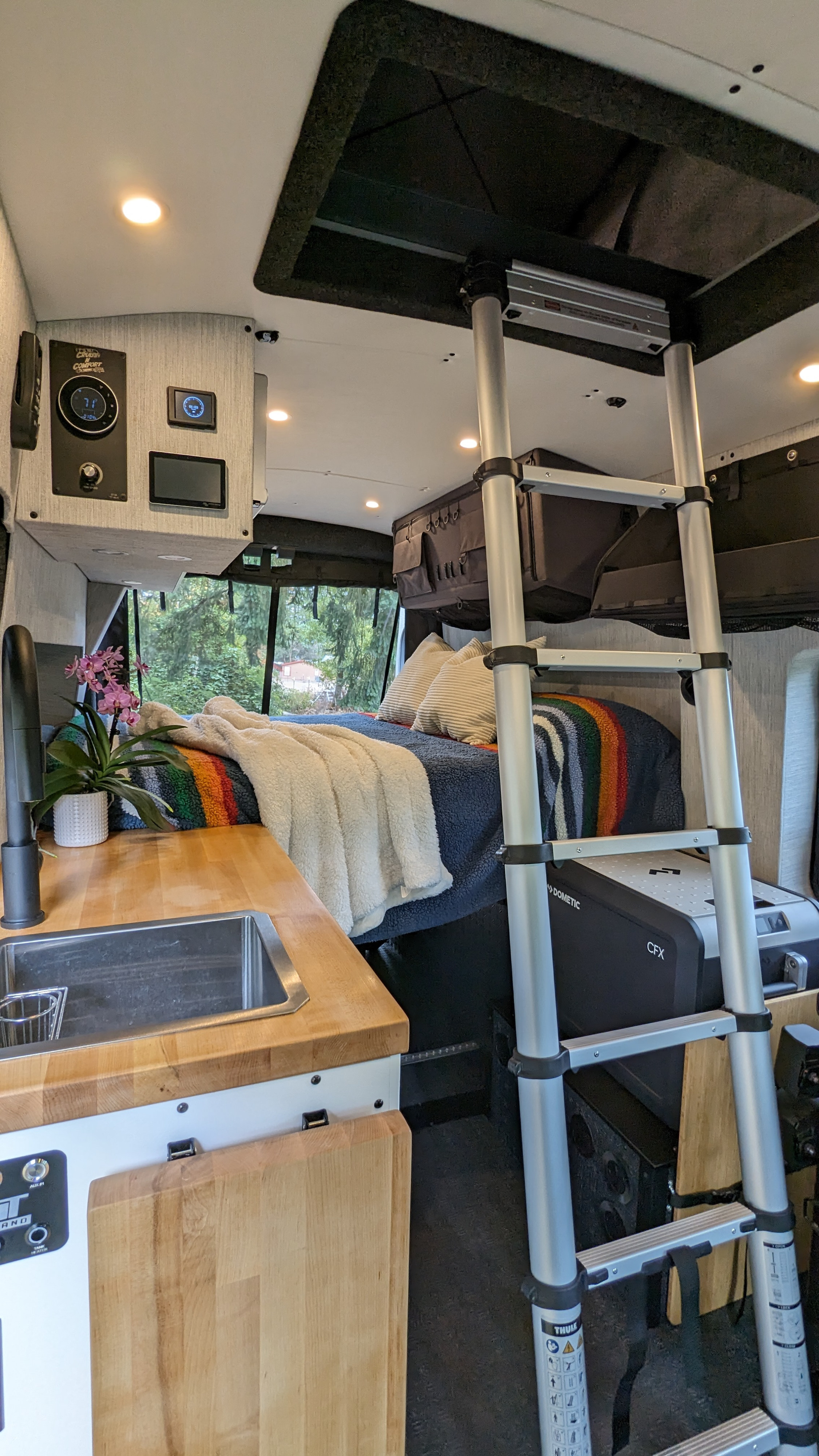 Inside a sleek rv rental: Compact kitchen, cozy bed, ladder to versatile overhead space, and Dometic cooler.. Ford Custom Transit 2022