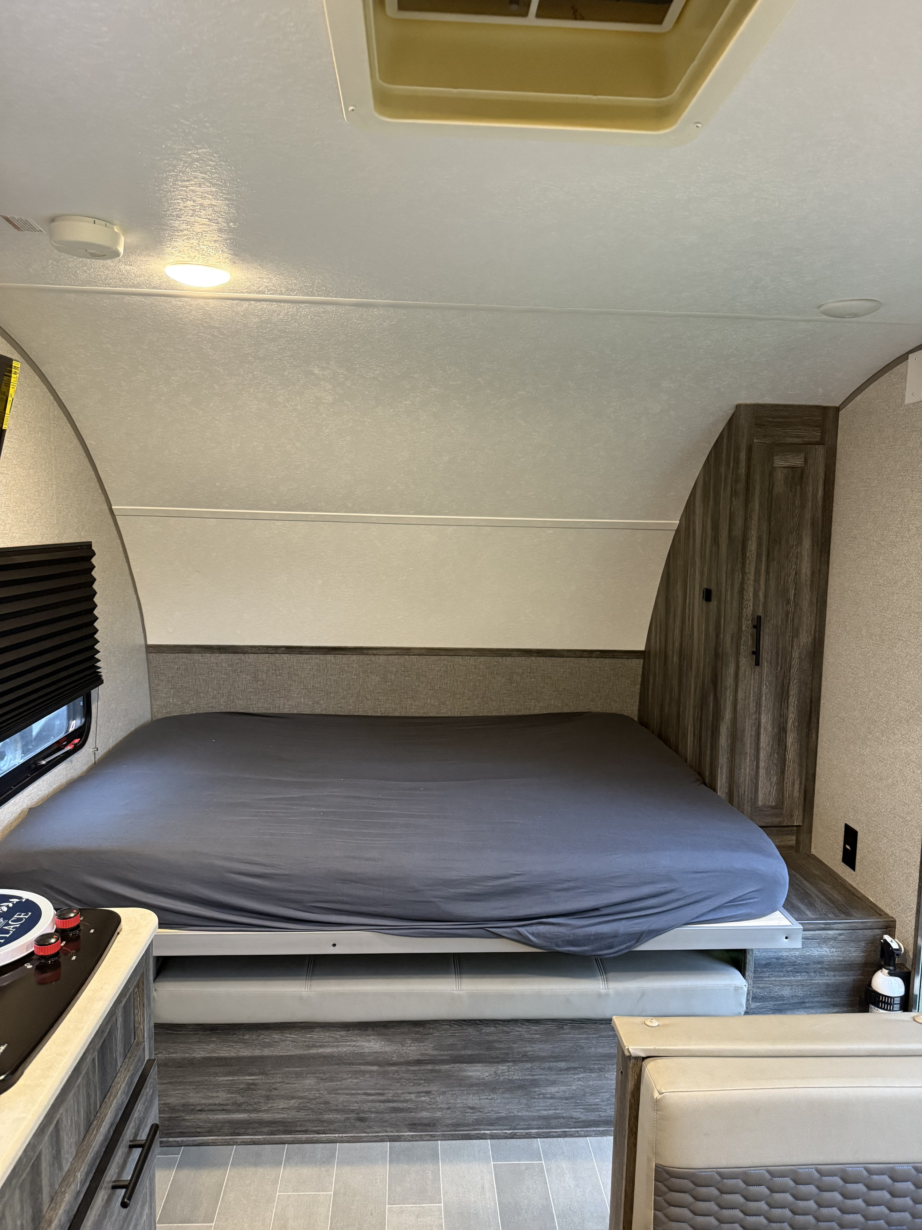 Inside an RV rental: a comfortable bed with grey sheet, mini kitchen, wardrobe, and dinette conversion space.. Forest River Salem FSX 2020