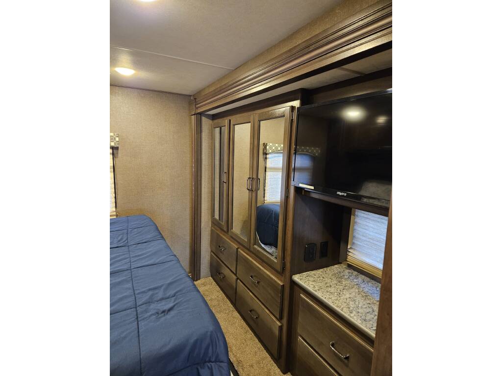 Explore the cozy bedroom of this RV rental, featuring a comfortable bed, mirrored closet, and flat-screen TV.. Thor Hurricane 2018