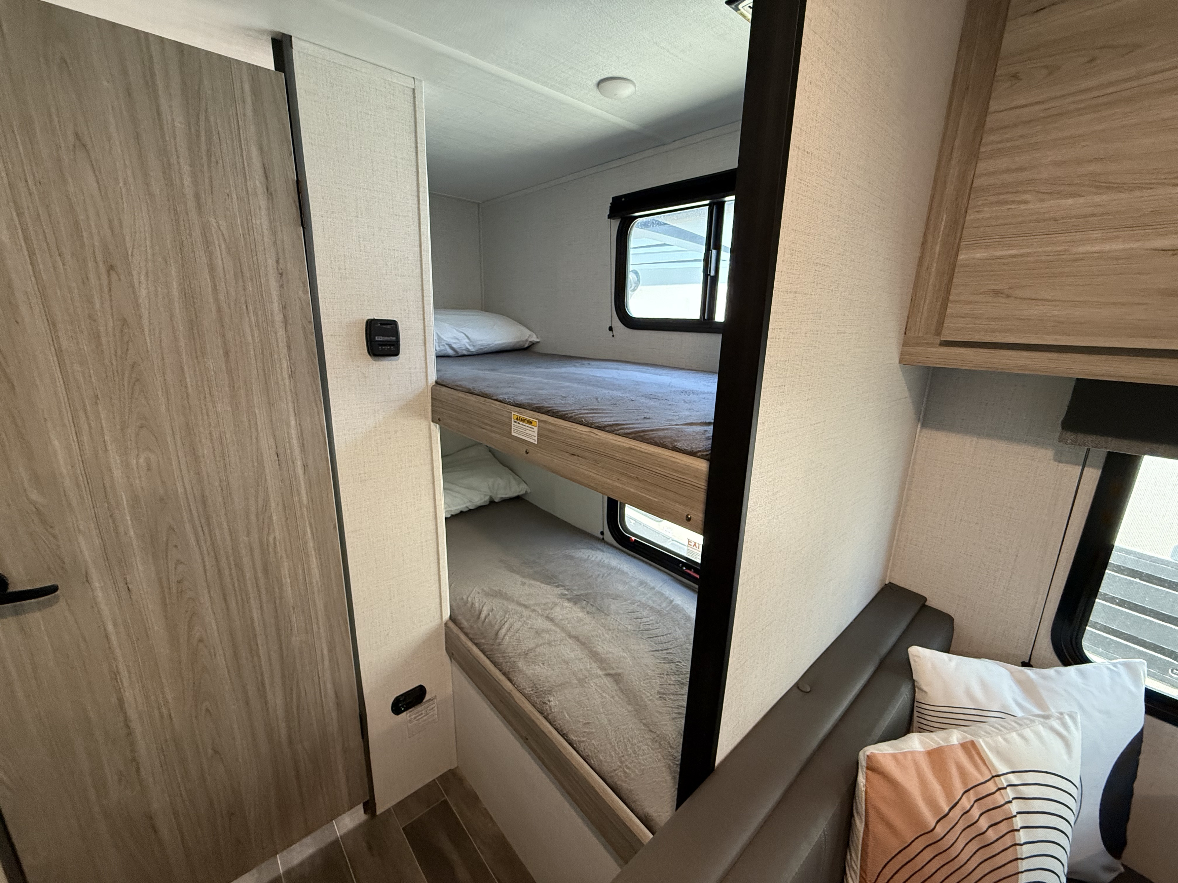 Inside this RV rental: two bunk beds, windows, and a comfortable seating area, maximizing compact living space.. Keystone RV Passport 170BH 2024