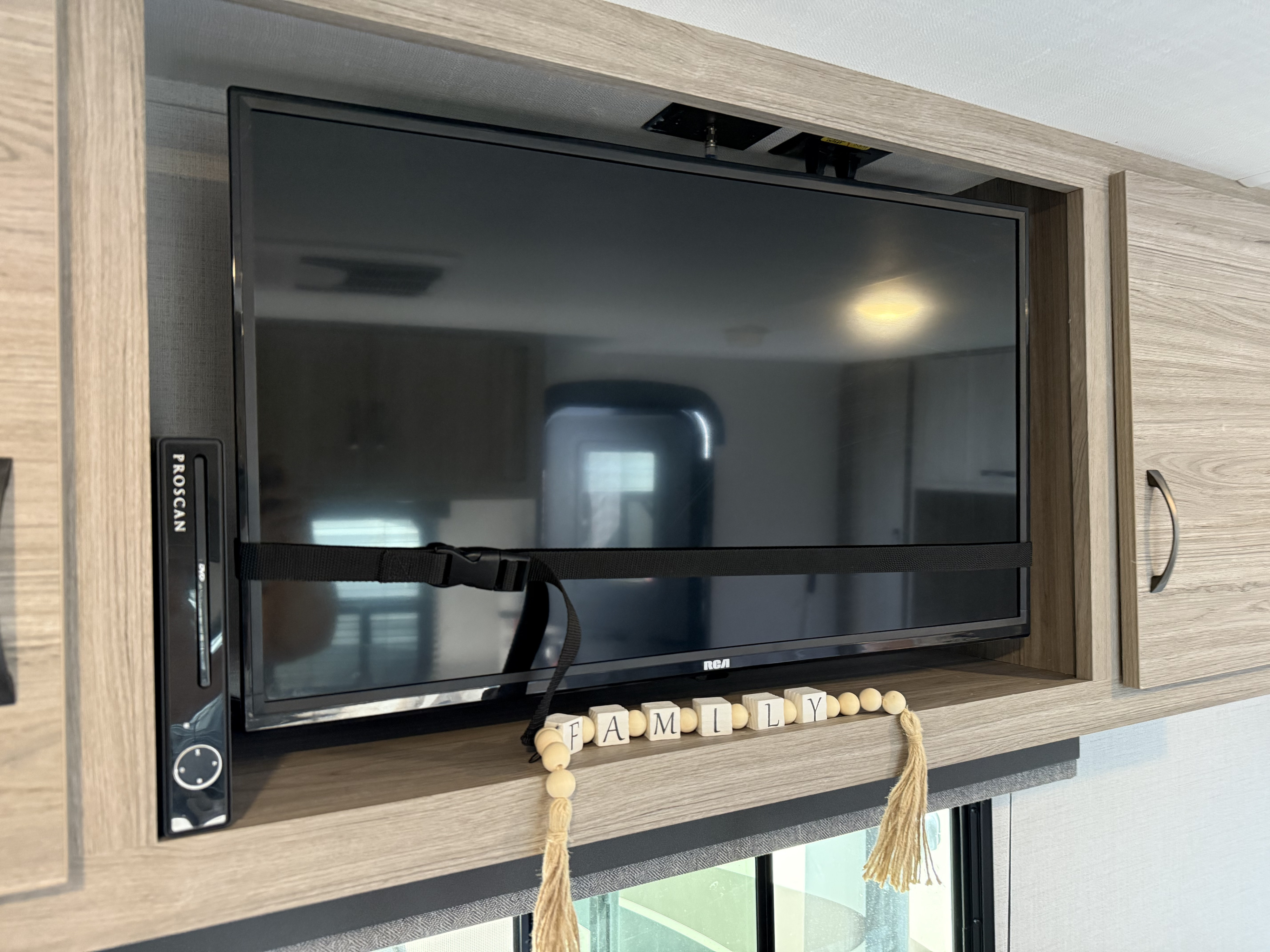 This RV rental features a compact TV and DVD player, secured by a strap within built-in cabinetry, perfect for travel entertainment.. Keystone RV Passport 170BH 2024