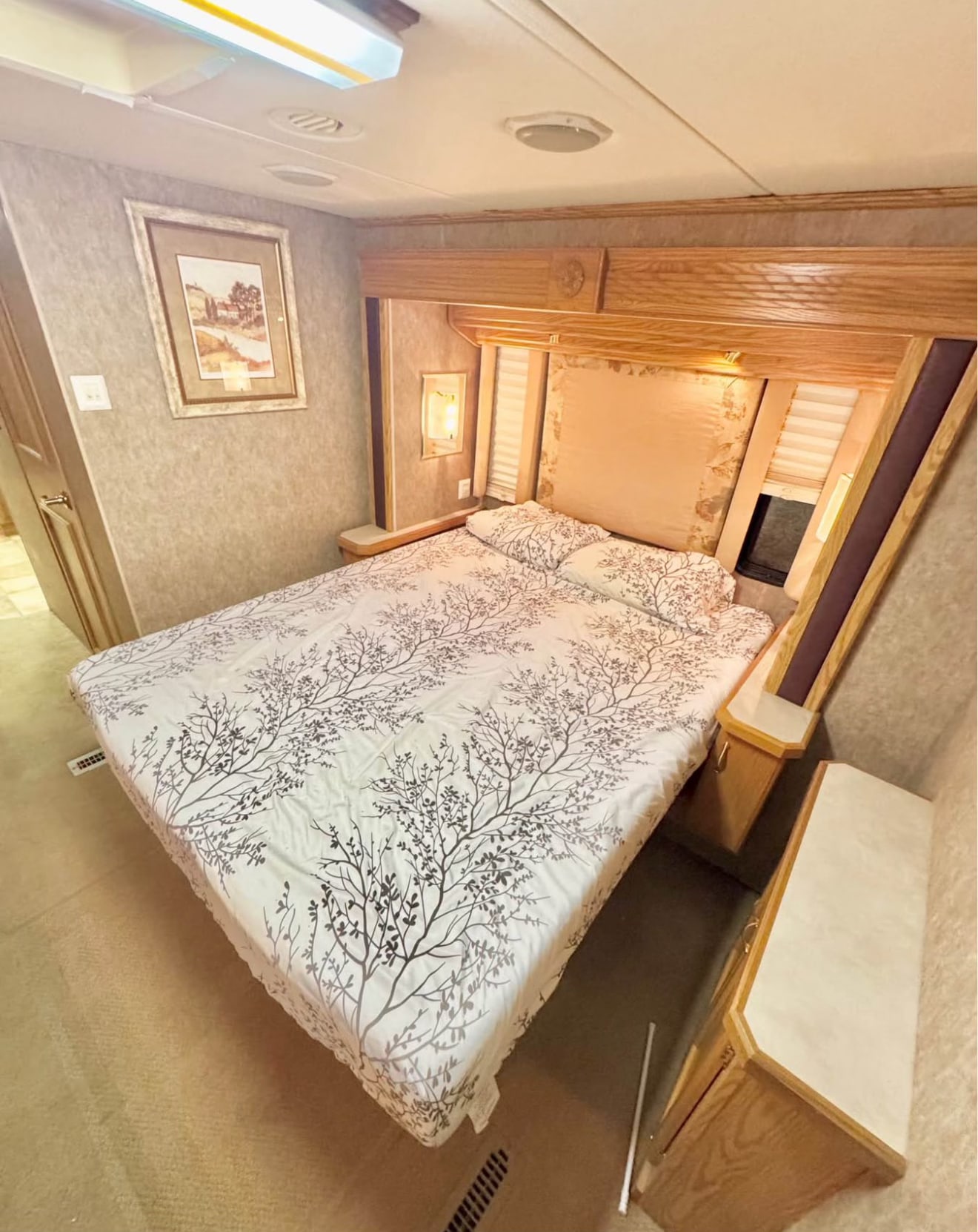 An inviting RV rental bedroom with a patterned bed, wood accents, and built-in storage.. Holiday Rambler Admiral SE 2005