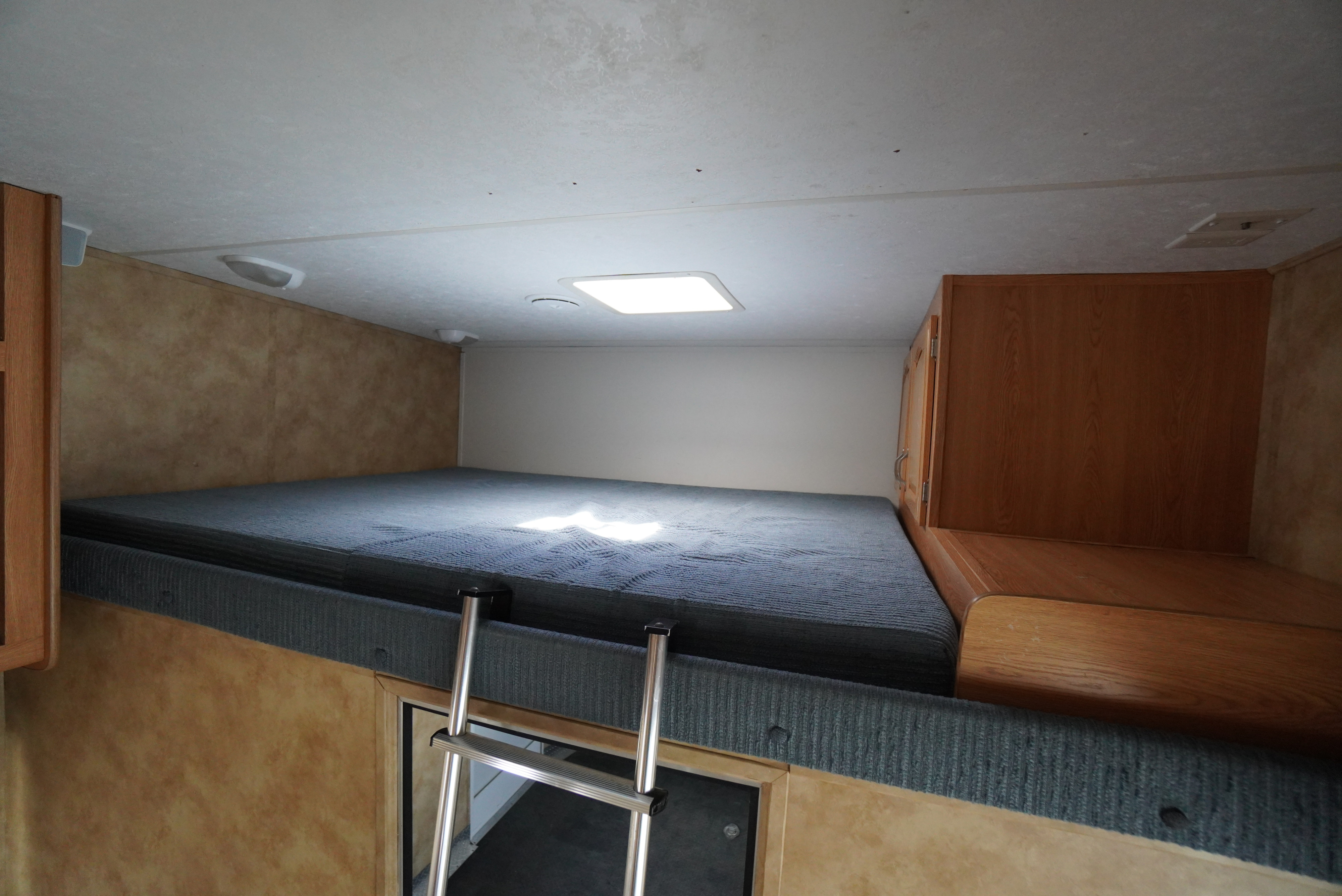 Inside this **RV rental**, discover a spacious bunk bed area with a ladder and storage, ready for your next adventure.. Keystone RV Raptor Toy Hauler 2006