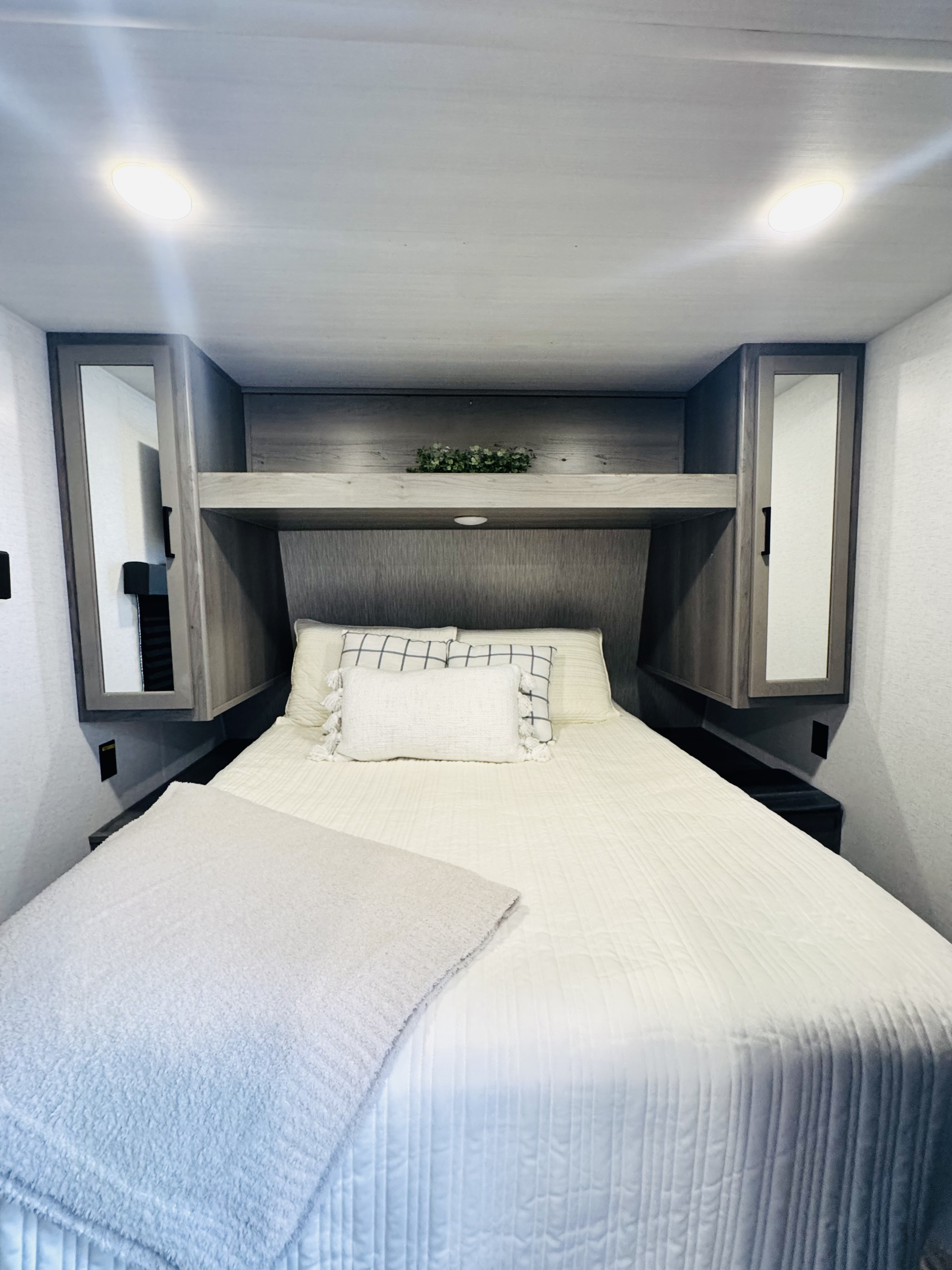 Experience comfort in this RV rental bedroom: large bed with soft bedding, mirrored cabinets, and ample storage for travel.. Keystone RV Hideout 2024