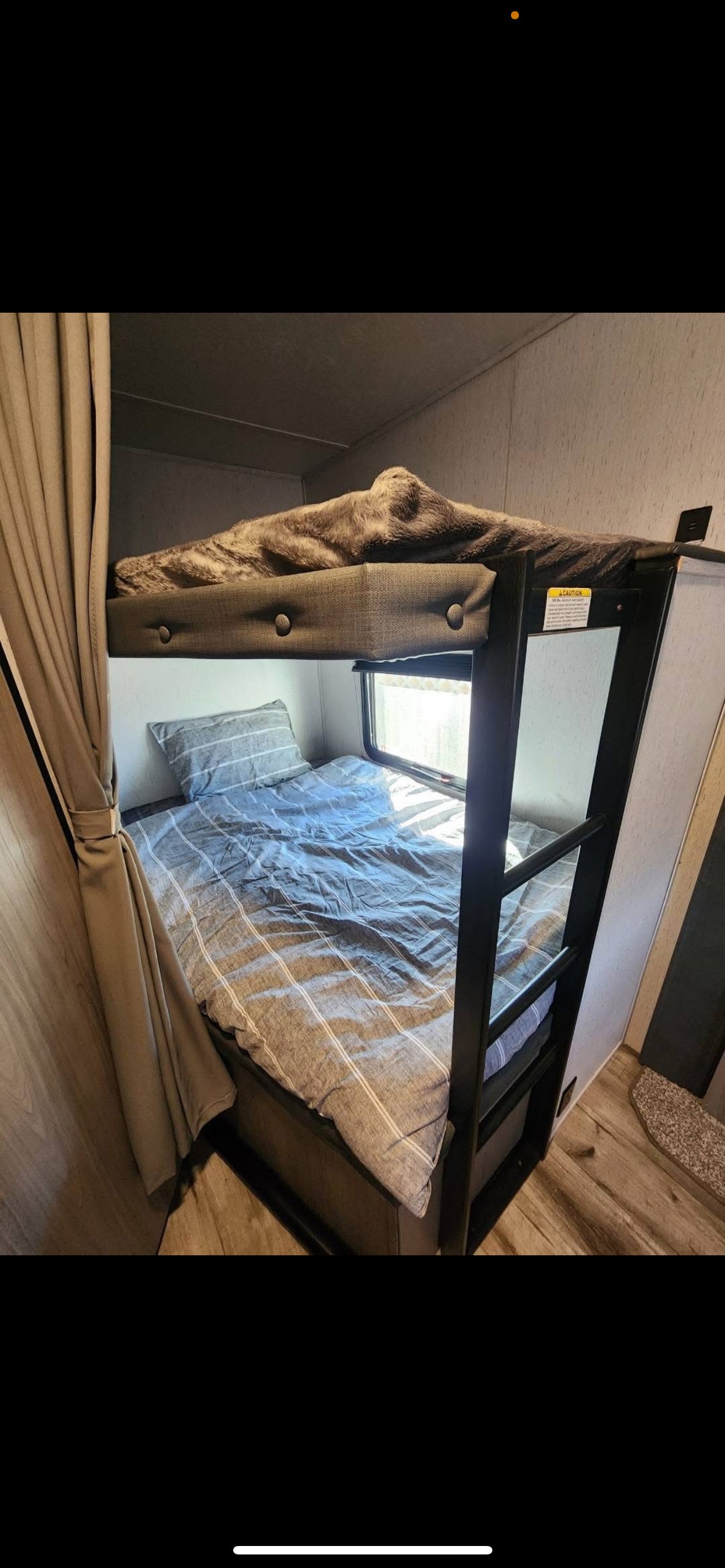 Cozy RV rental bunk beds: top bunk with furry blanket, bottom with striped bedding & window. Perfect for family adventures.. Dutchmen Coleman Lantern 2022