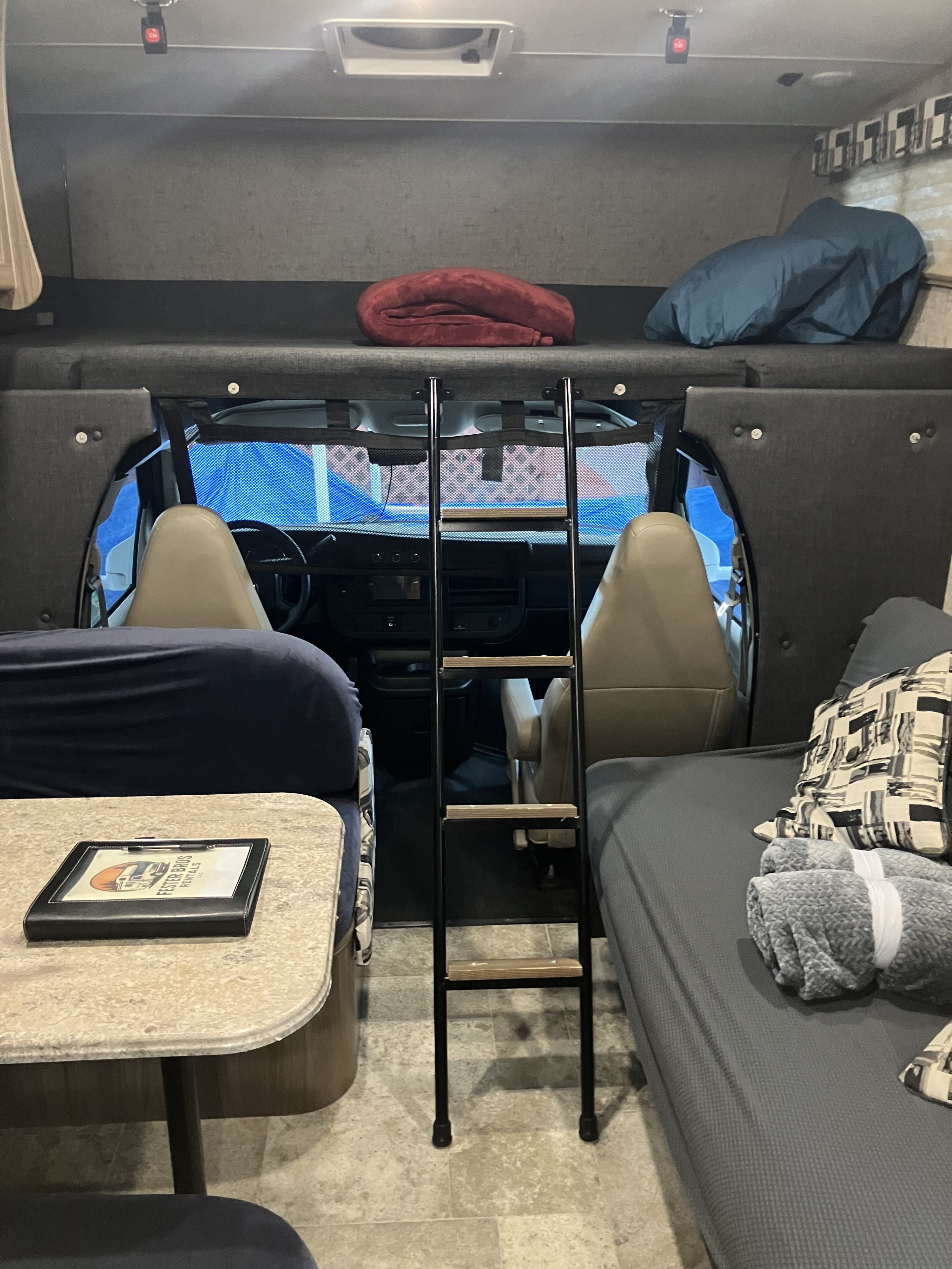 RV rental interior with an overhead bunk, ladder, dinette, and front cab view.. Forest River Coachmen Freelander 2017