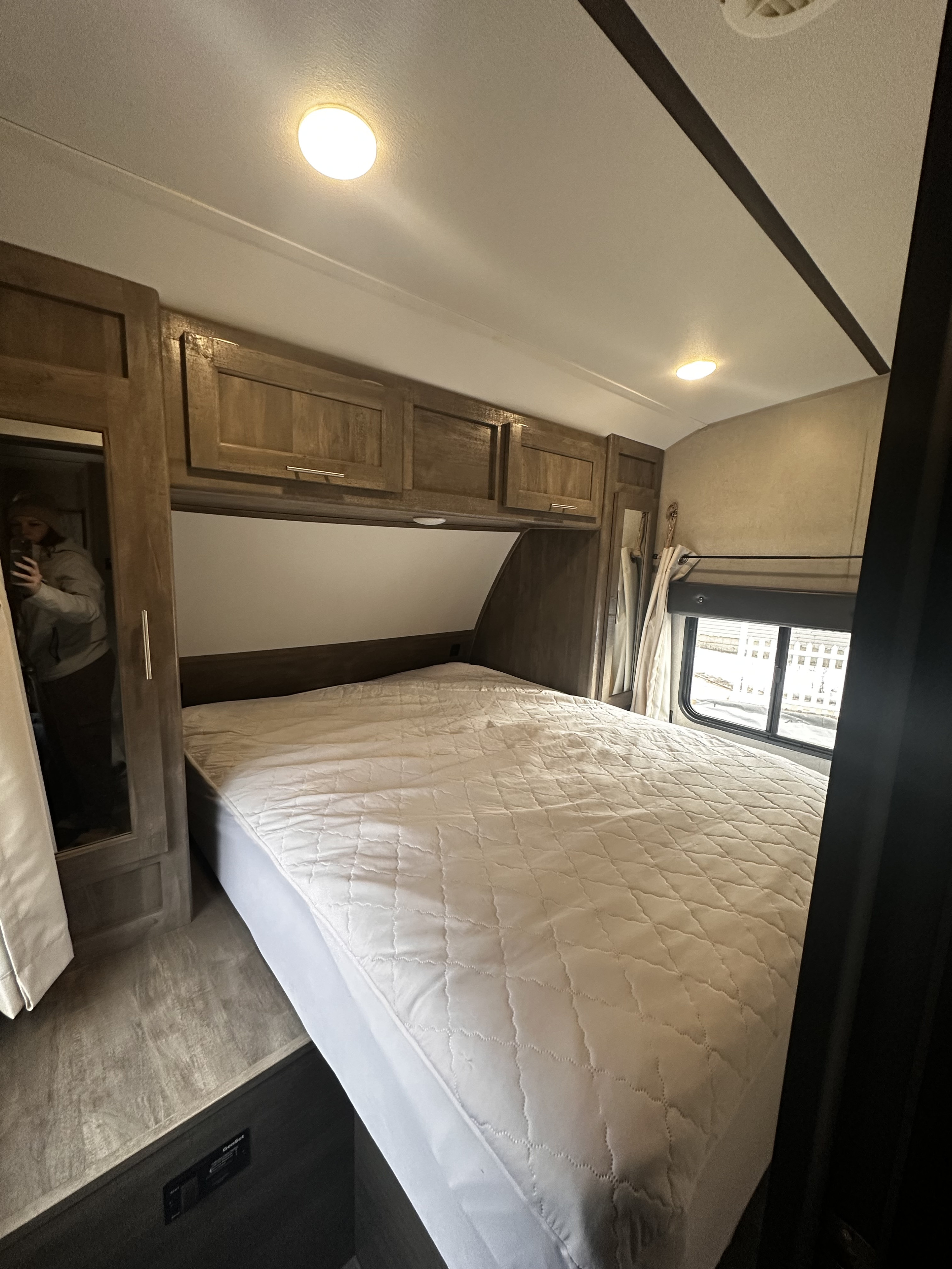 Spacious RV rental bedroom showcasing a comfortable bed, modern cabinets, window view, and Genset controls.. Forest River XLR Boost 29QBS 2020