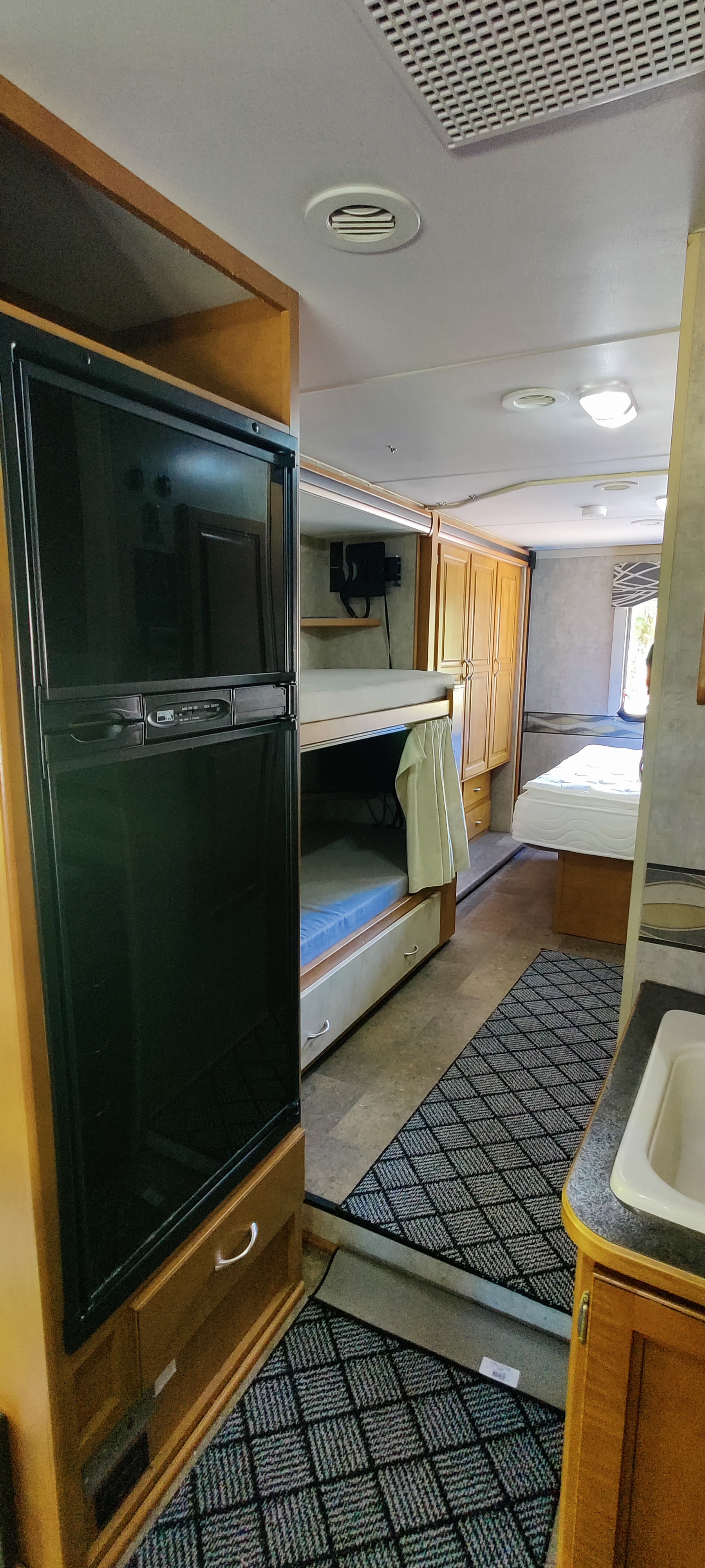 Spacious RV rental interior: large fridge, bunk beds, cabinets, and a rear bedroom for comfortable travel.. Itasca Spirit 2014