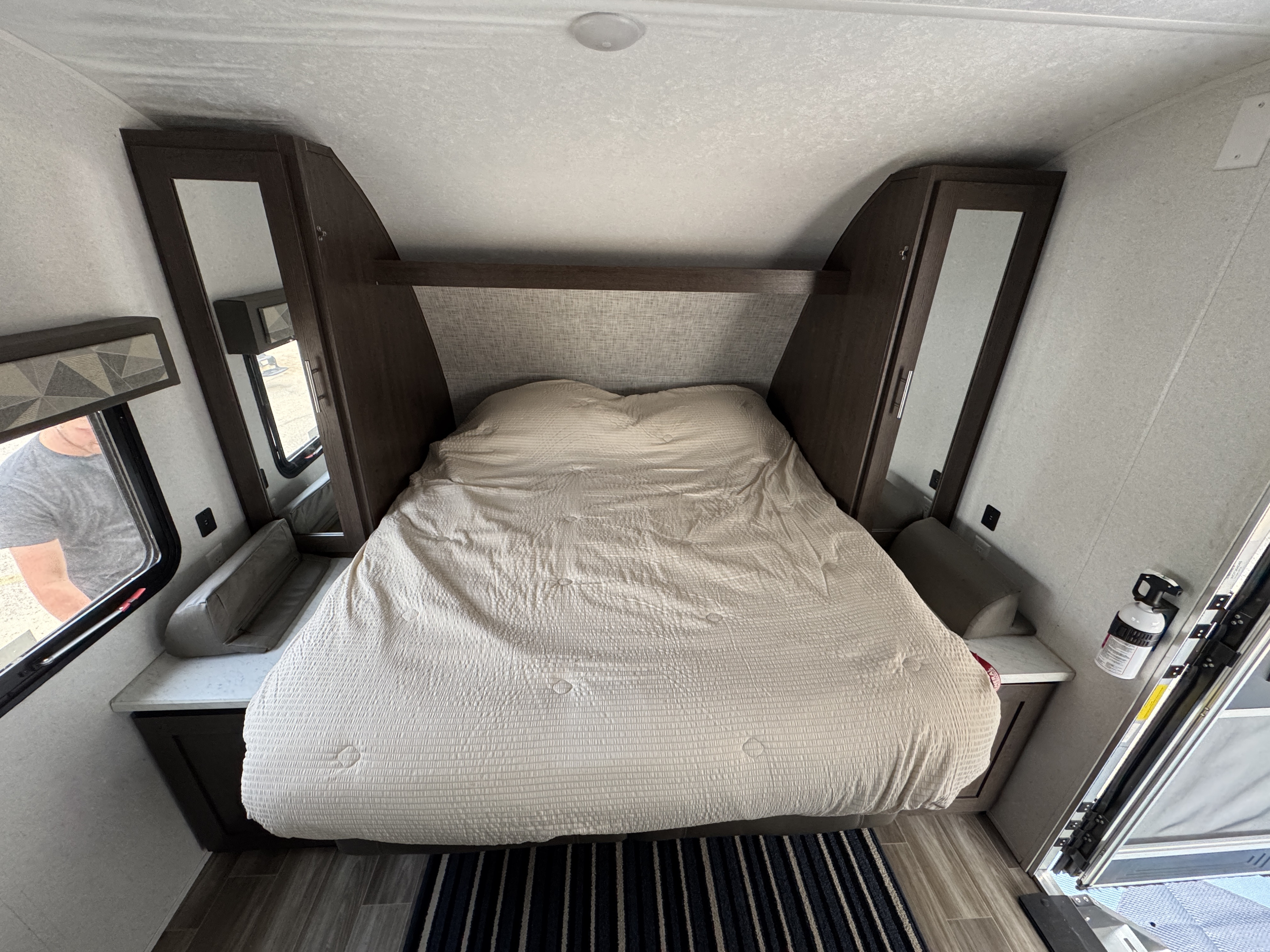 Inside this RV rental: A cozy bedroom with bed, overhead shelf, and storage cabinets, offering comfort on the road.. Forest River Wildwood X-Lite 2019
