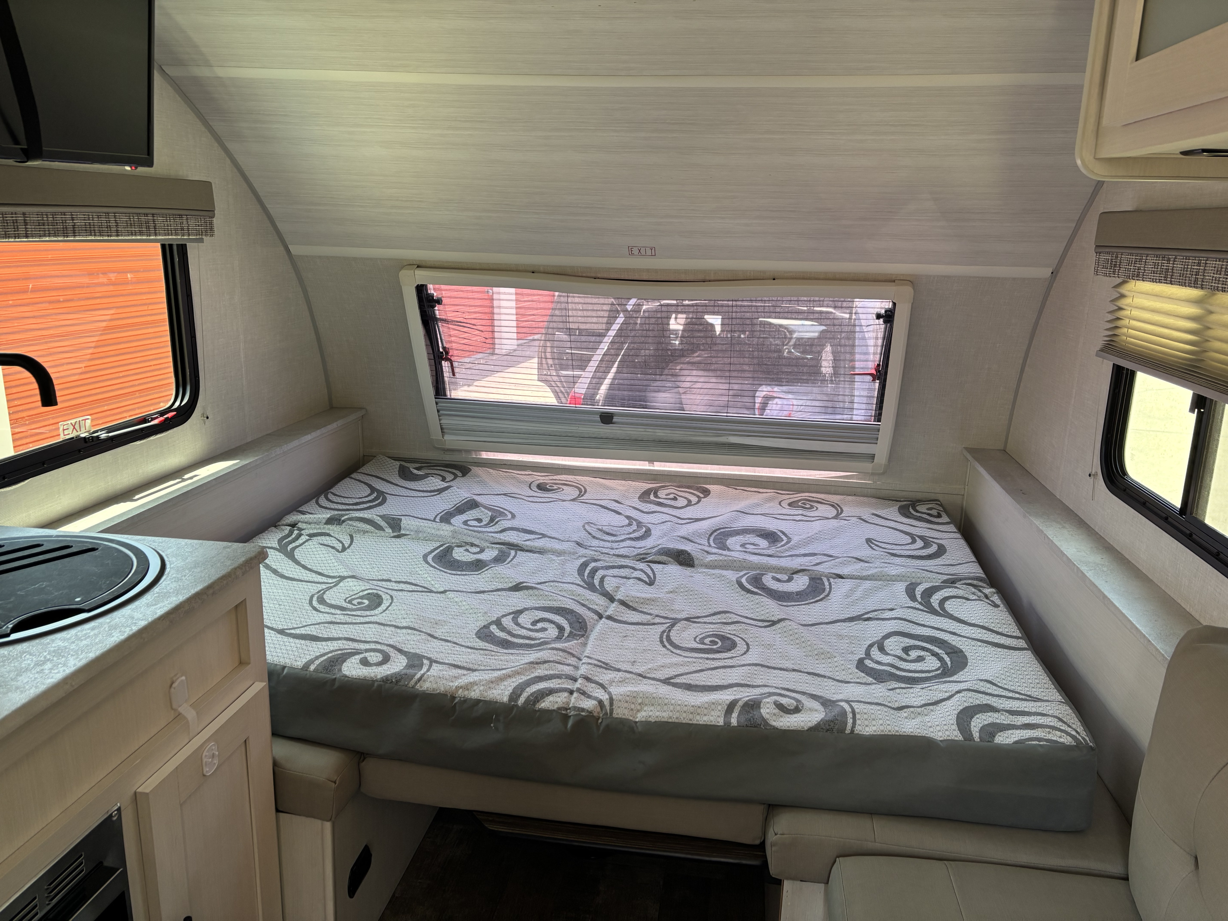 Spacious RV rental interior featuring a comfortable bed, windows with blinds, and a compact kitchen counter.. Forest River R-Pod 153 2022
