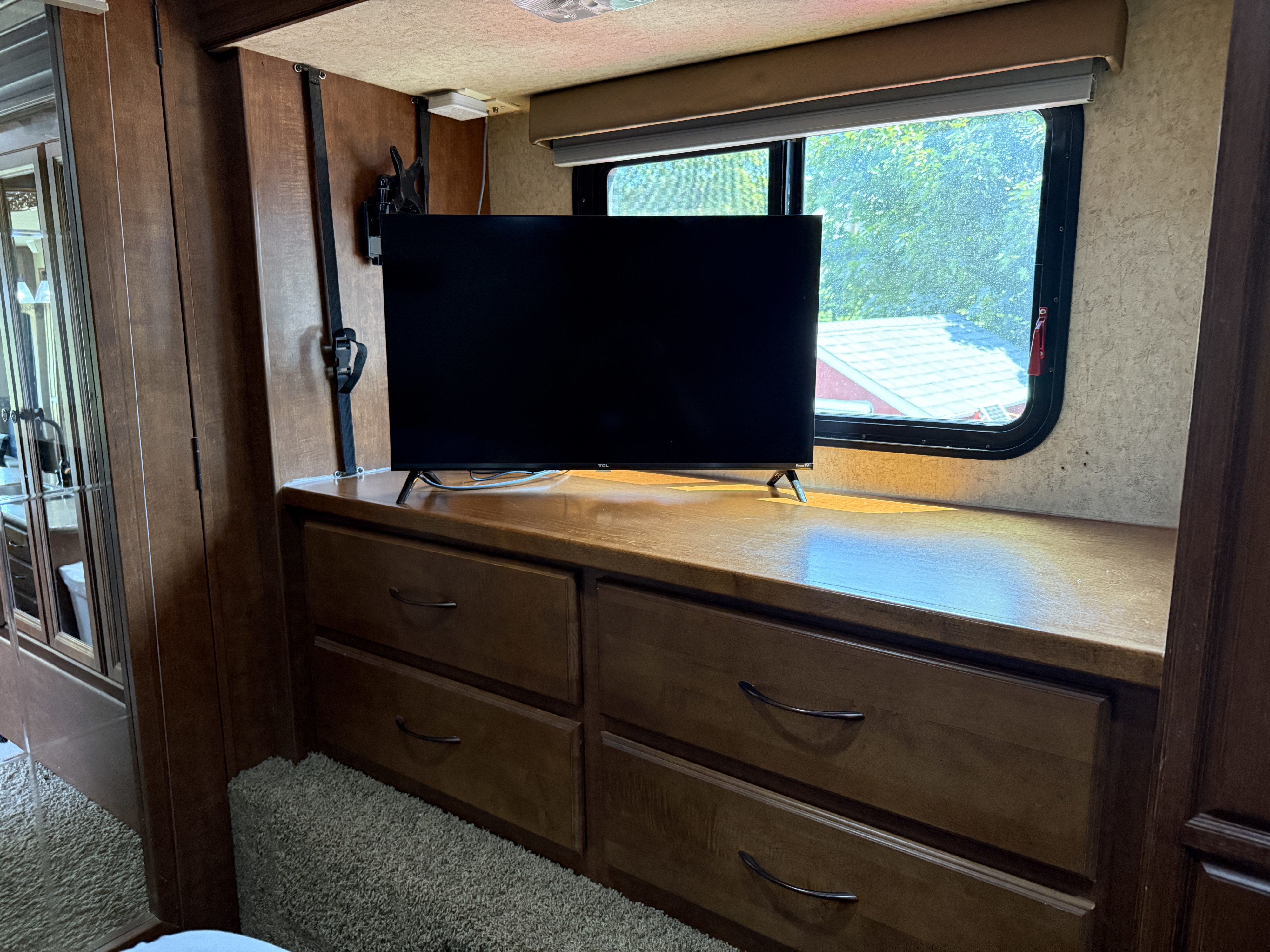 RV rental: View of a TV on a wooden dresser with multiple storage drawers, next to a window and carpeted floor.. Heartland RVs Bighorn 2012